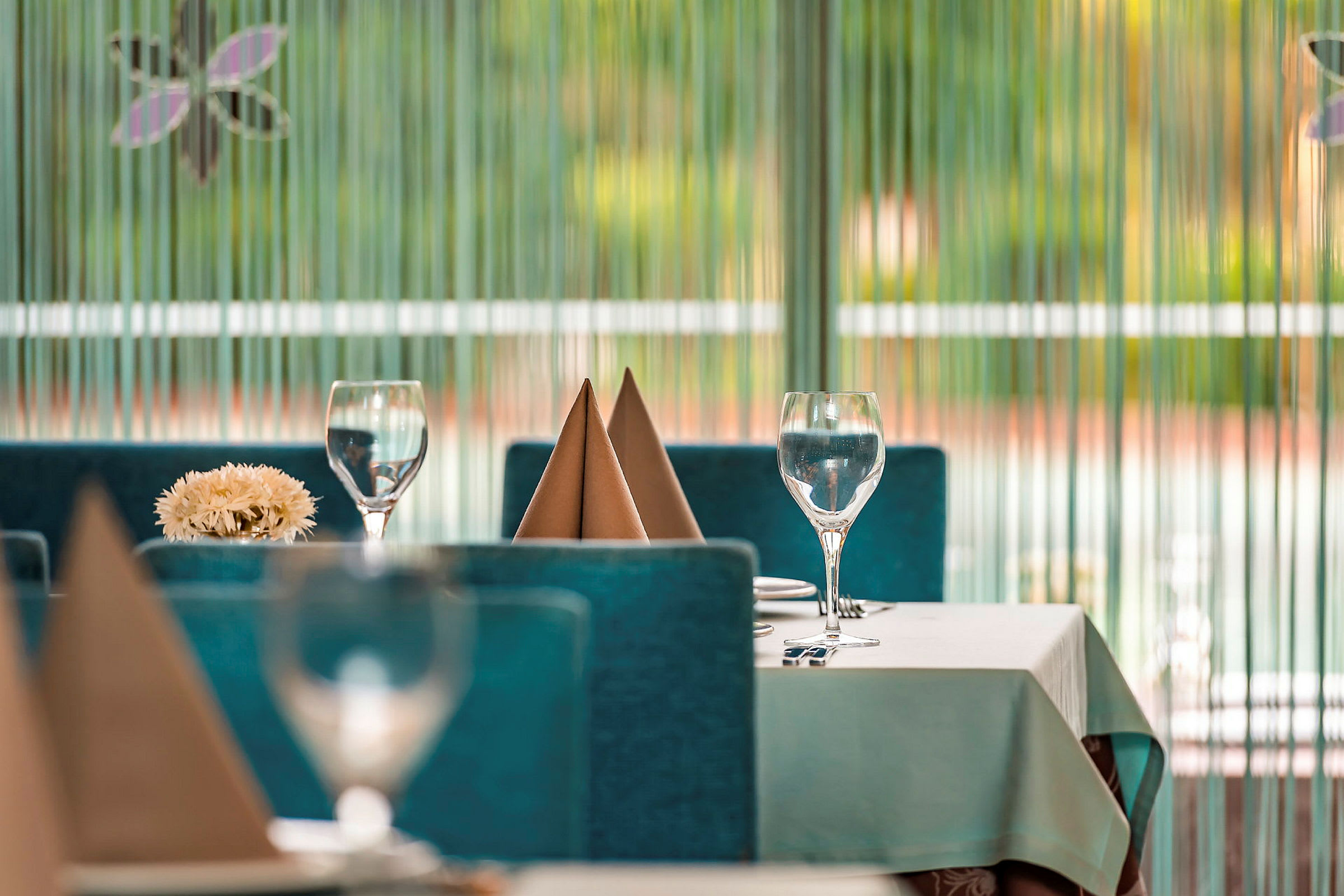 Pænt dækket bord med glas og servietter i restaurantmiljø. (AI-genereret tekst)