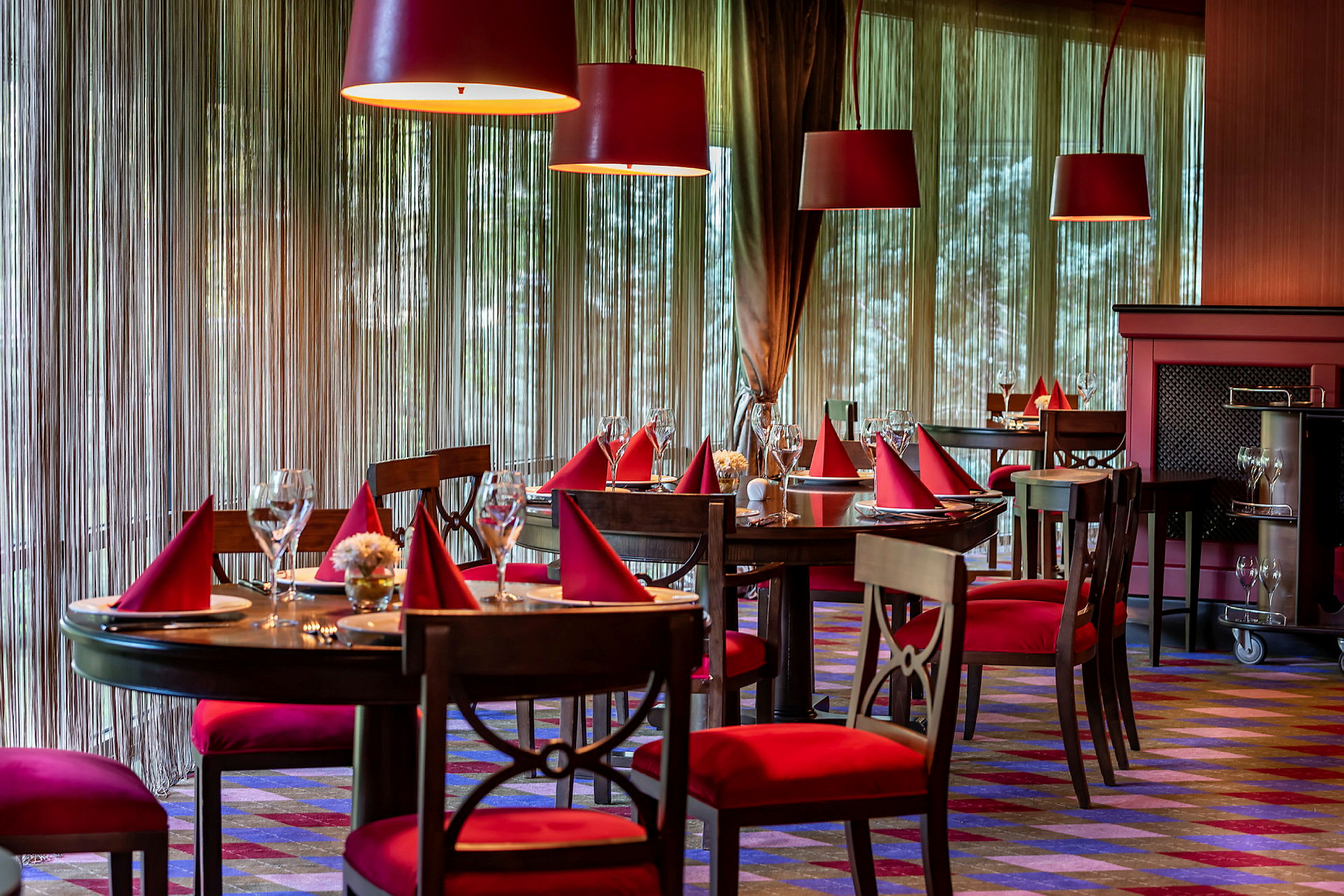 En elegant restaurant med borde dækket med røde servietter og glas. (AI-genereret tekst)
