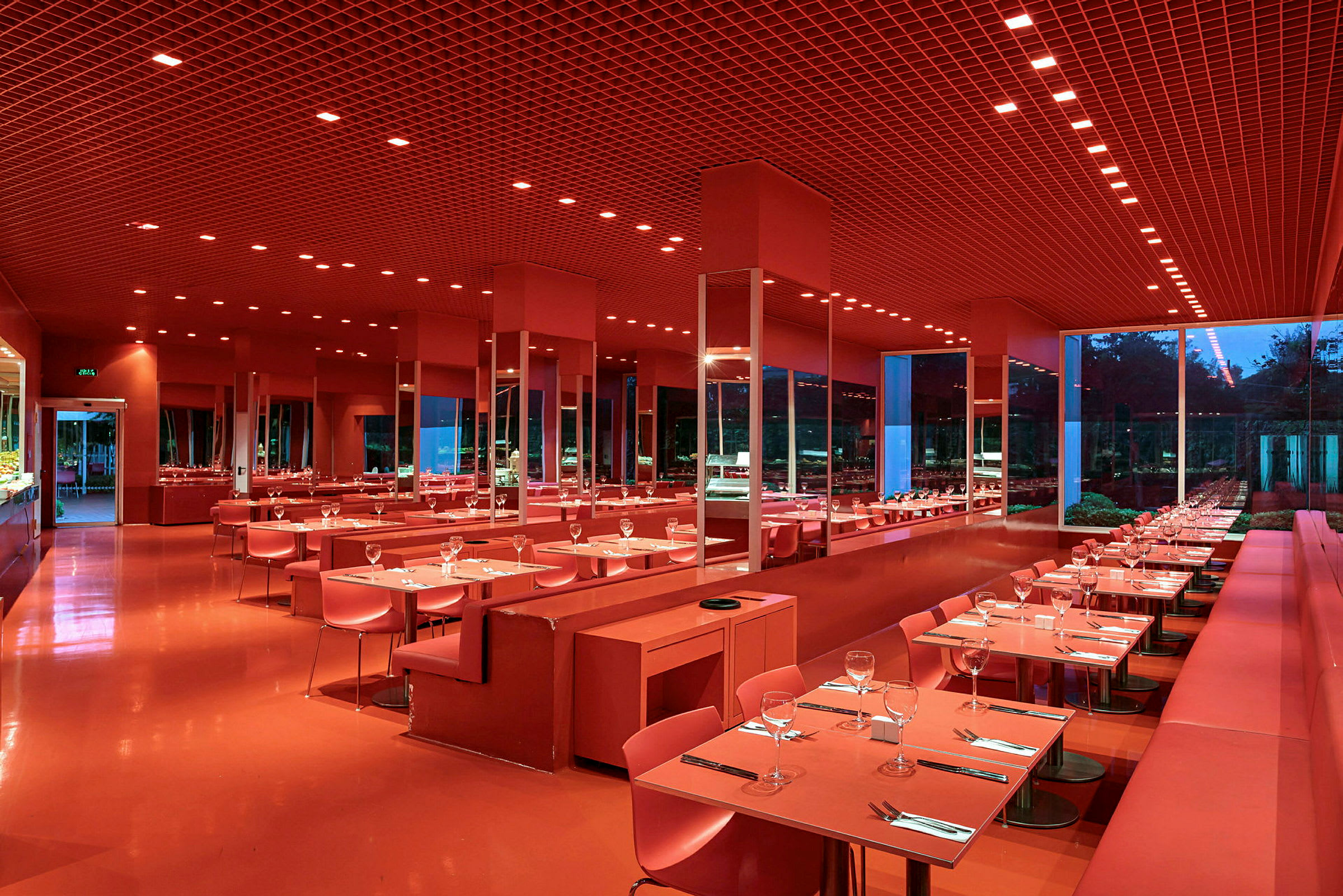 En moderne restaurant med rød indretning, opdækkede borde og store vinduer. (AI-genereret tekst)