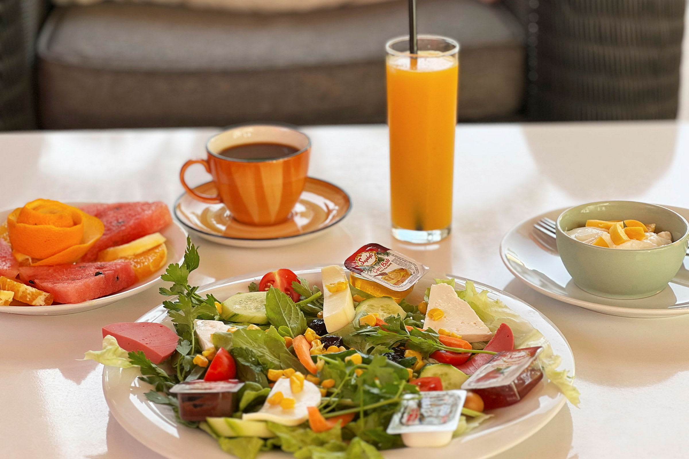 En morgenmad med salat, frugt, juice, kaffe og yoghurt. (AI-genereret tekst)