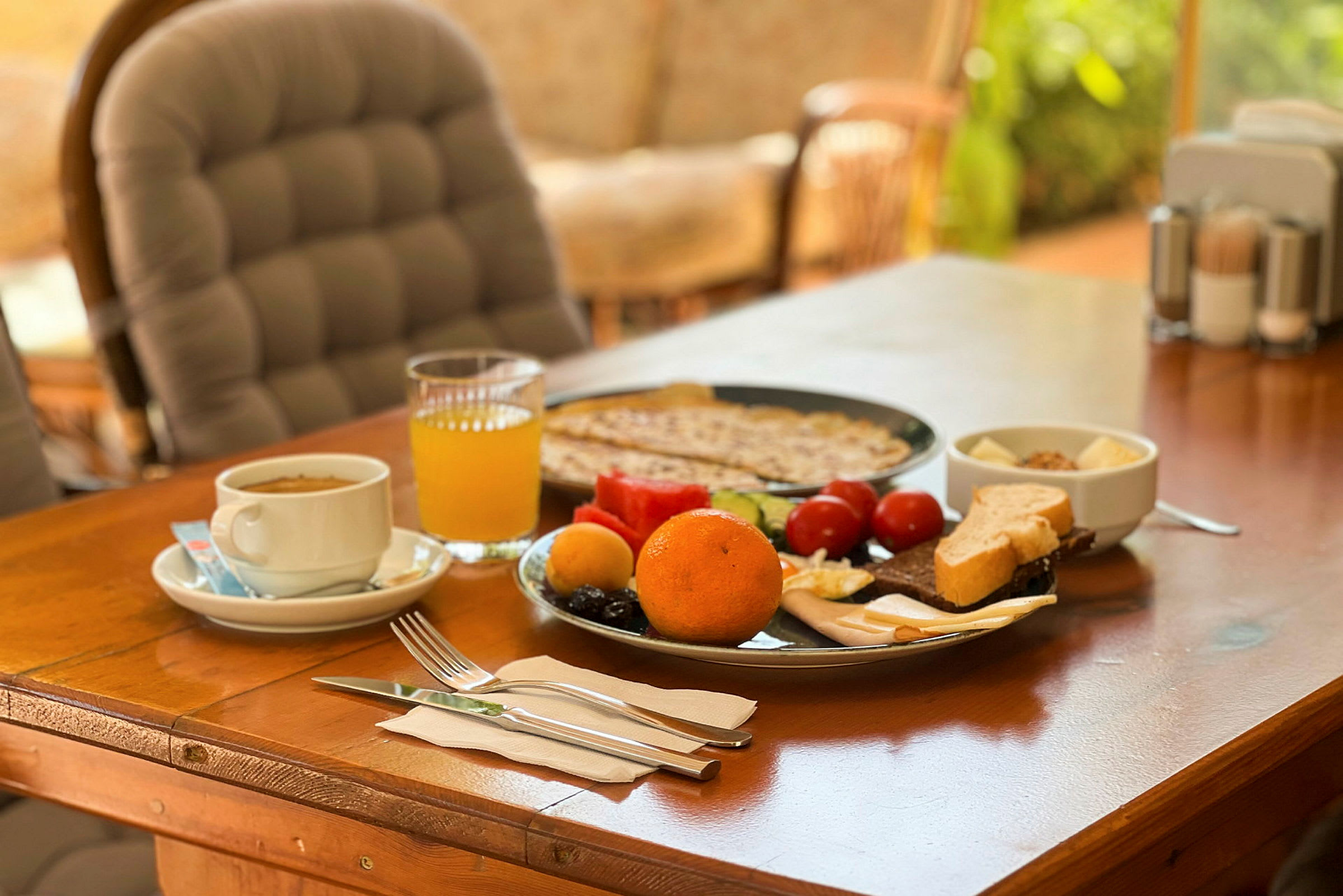 Morgenmad med appelsin, juice, brød og grøntsager på bordet. (AI-genereret tekst)
