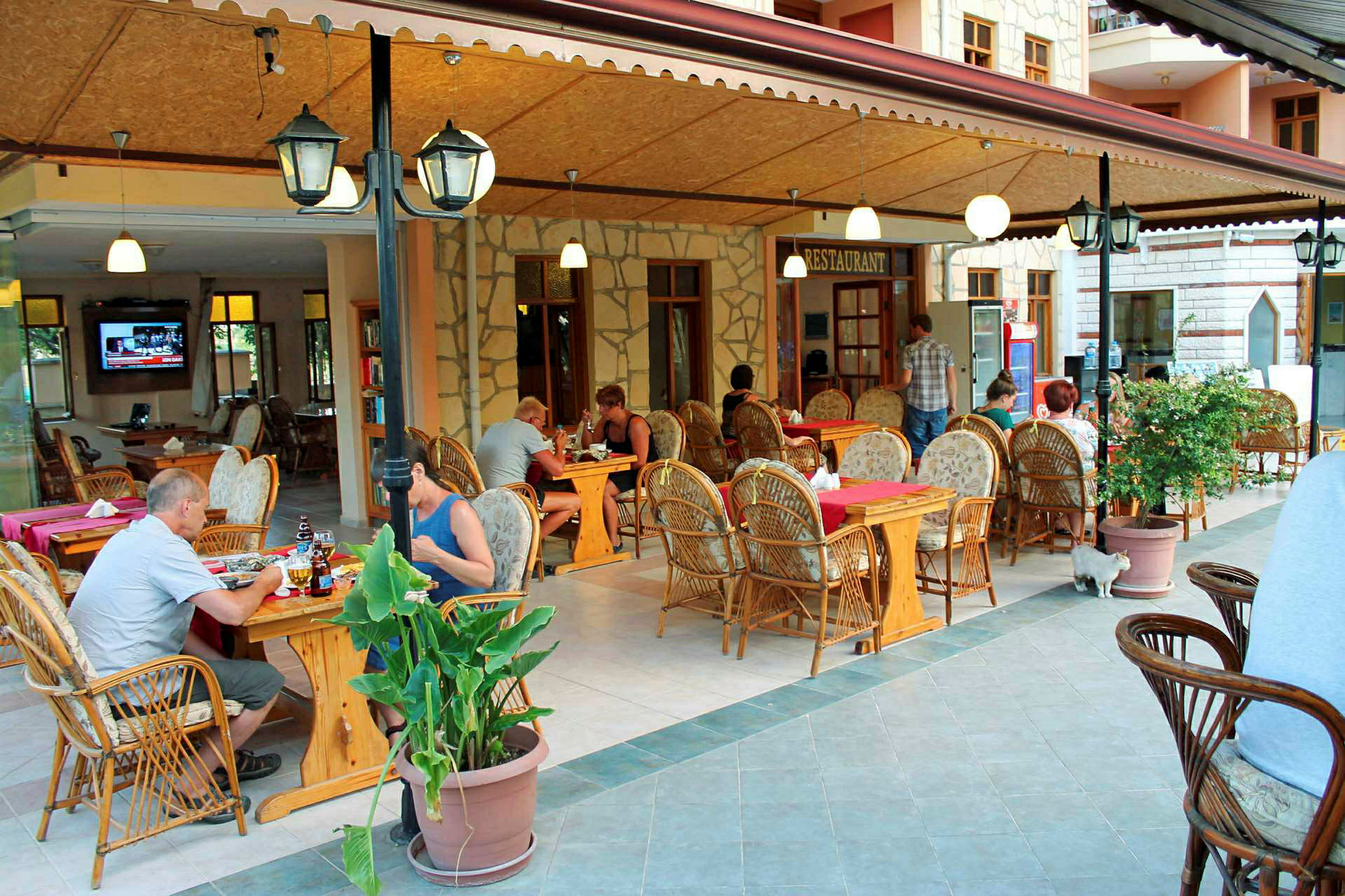En restaurant med udendørs servering og møbler af rattan. (AI-genereret tekst)