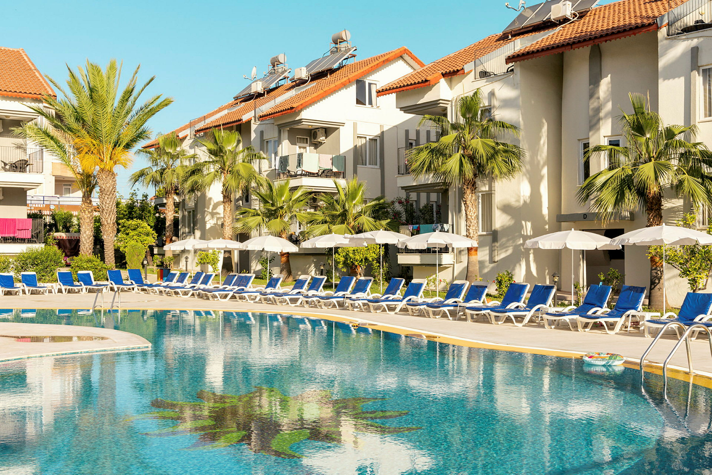 Udendørs pool ved hotel med liggestole og parasoller. (AI-genereret tekst)