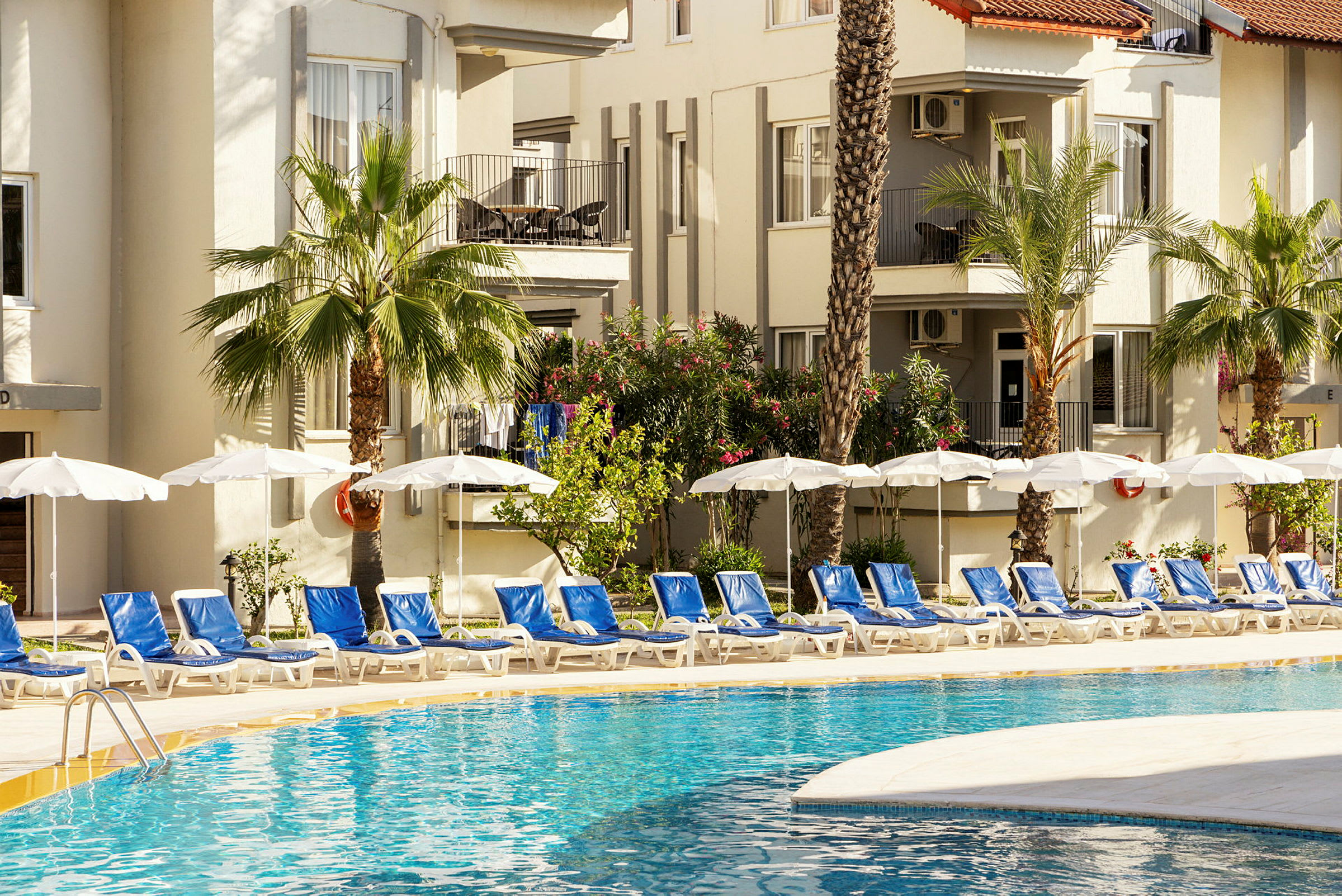 En pool med liggestole og parasoller ved et hotel. (AI-genereret tekst)