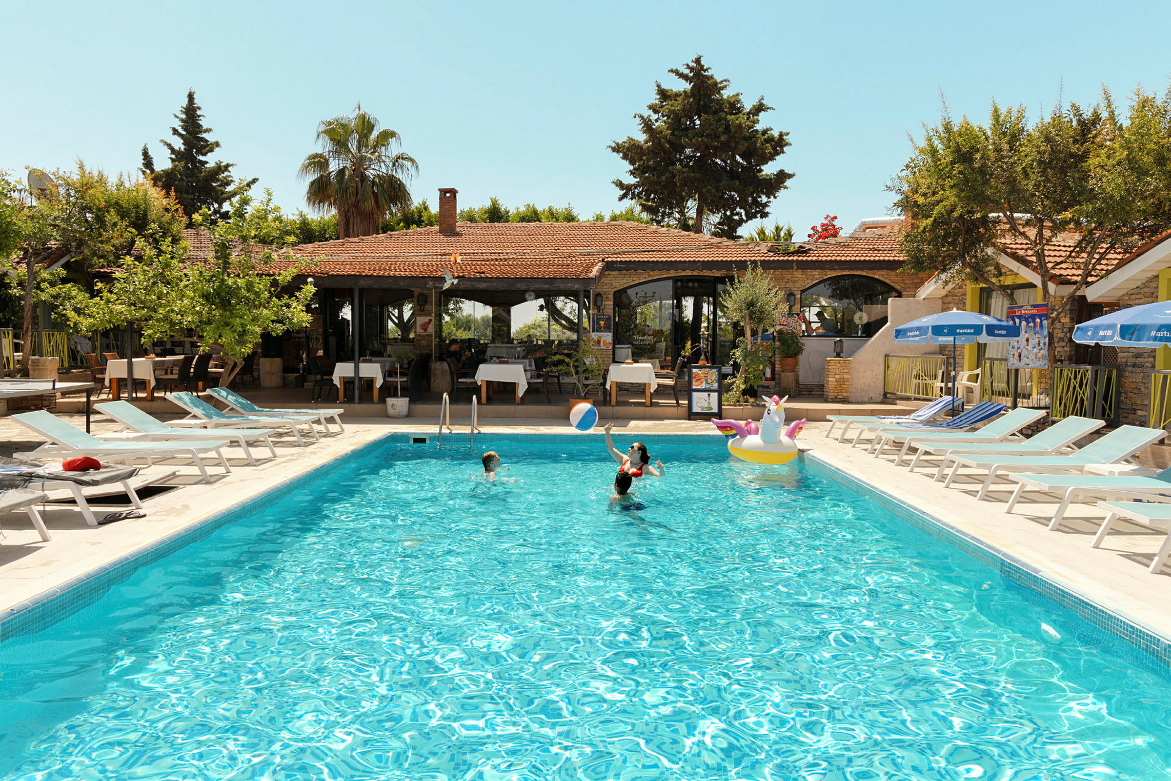 Udendørs swimmingpool med mennesker, der bader ved en feriebolig. (AI-genereret tekst)