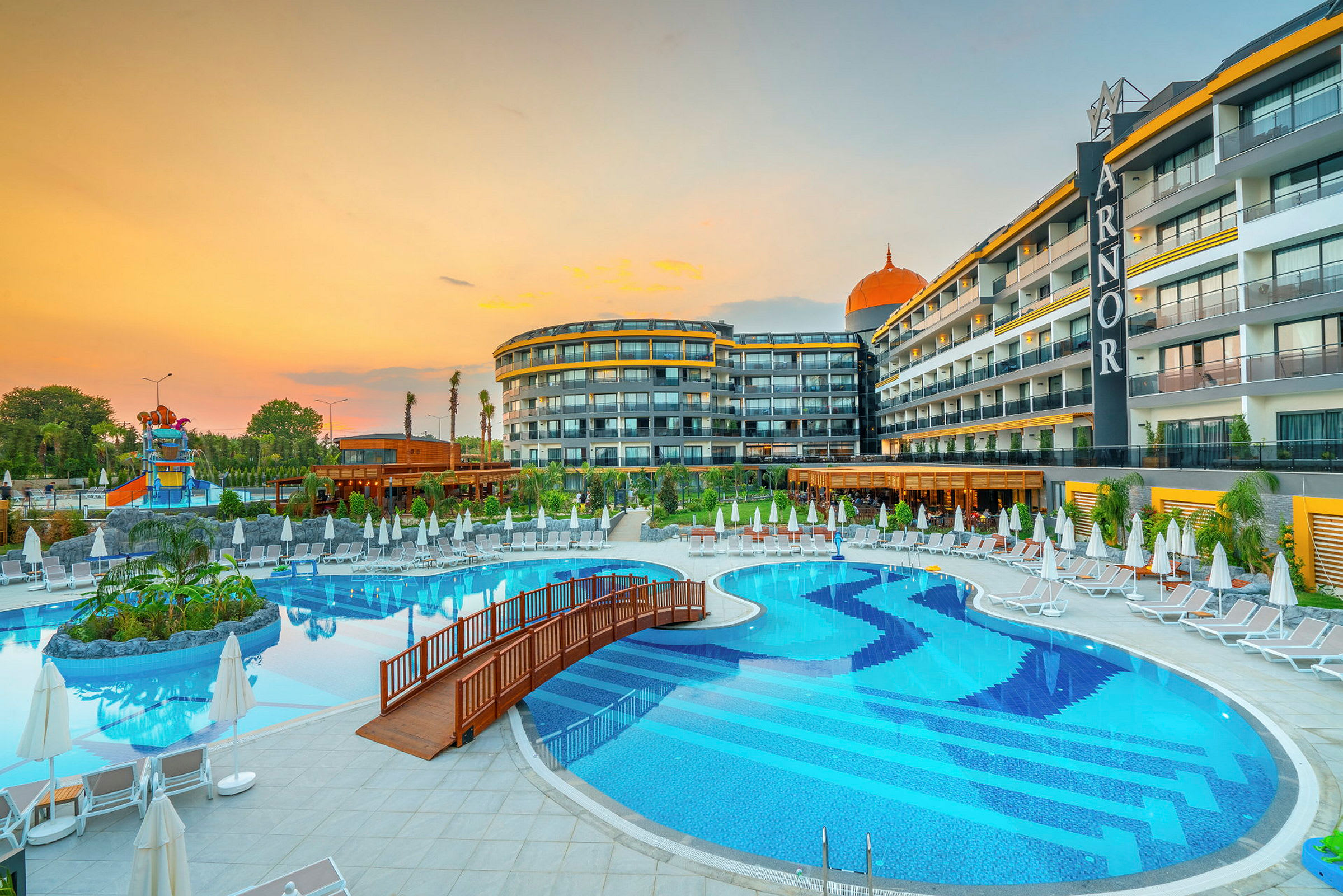 En udendørs pool med liggestole og parasoller ved siden af et hotel. (AI-genereret tekst)
