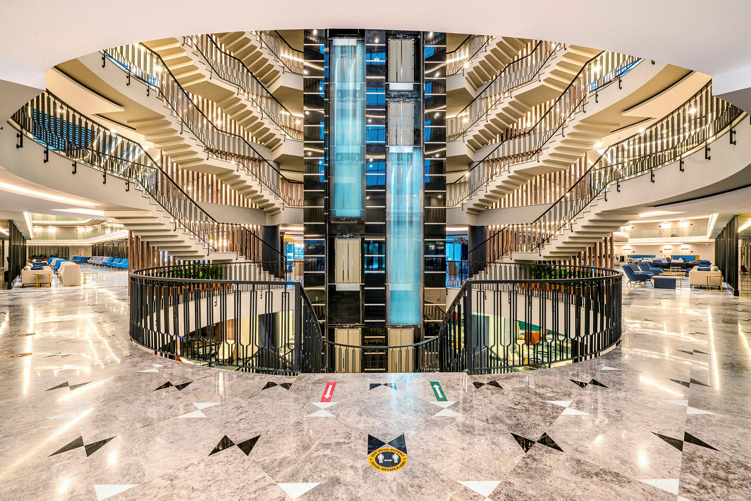 Hotellets atrium med belysningsdesign, glaselevatorer og trapper, der fører opad. (AI-genereret tekst)