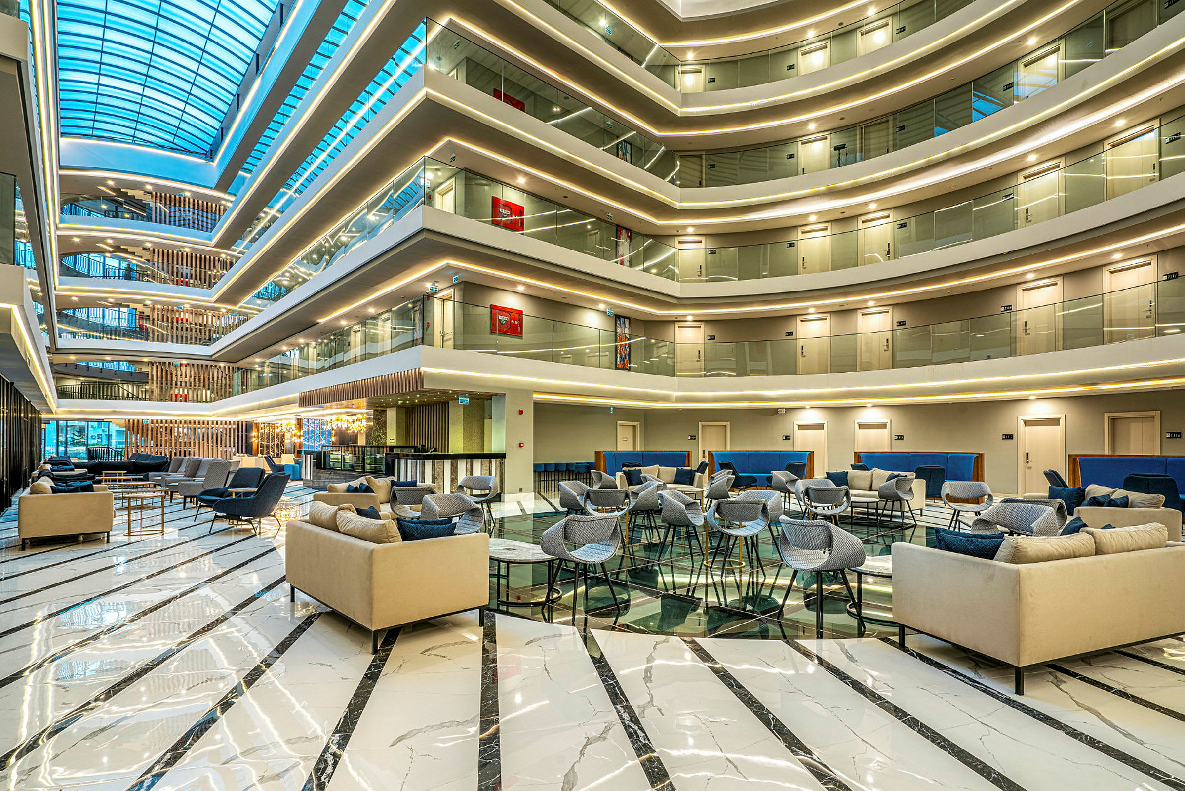 Moderne loungemøbler i en rummelig hotellobby med et glasloft. (AI-genereret tekst)