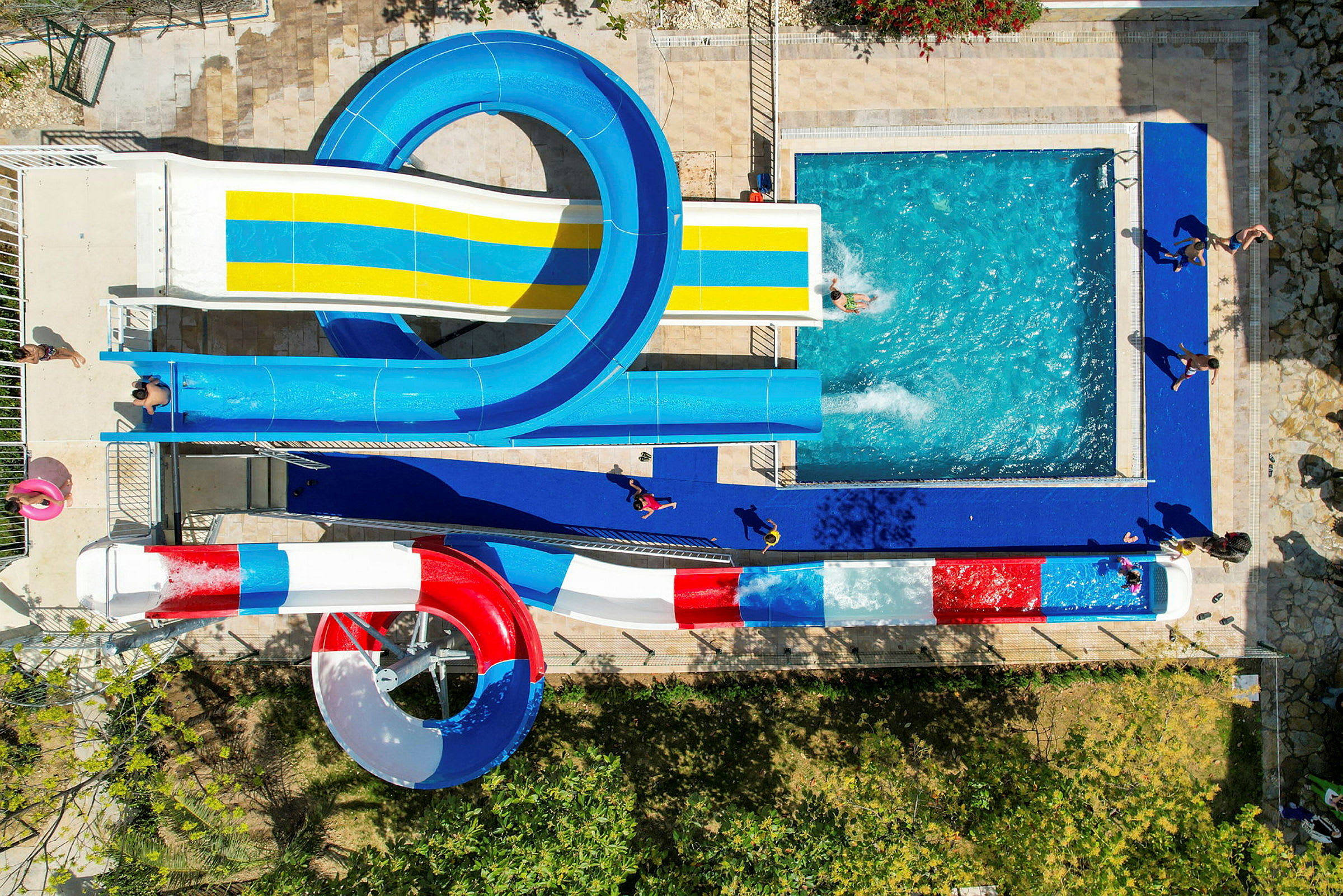 Billede af en vandpark med flere vandrutsjebaner, der fører til en pool. (AI-genereret tekst)