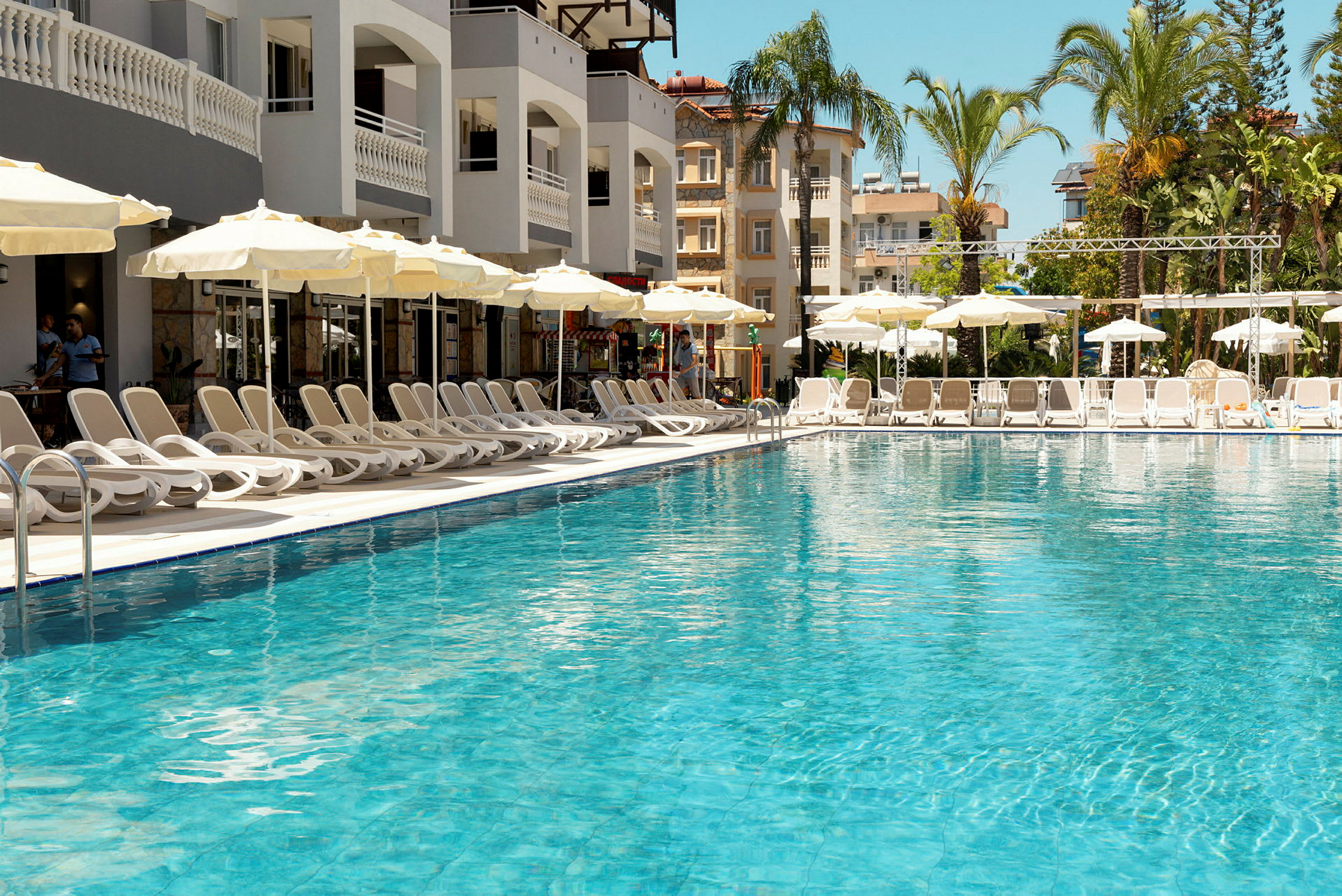 Udendørs swimmingpool med liggestole og parasoller ved hotelkompleks. (AI-genereret tekst)