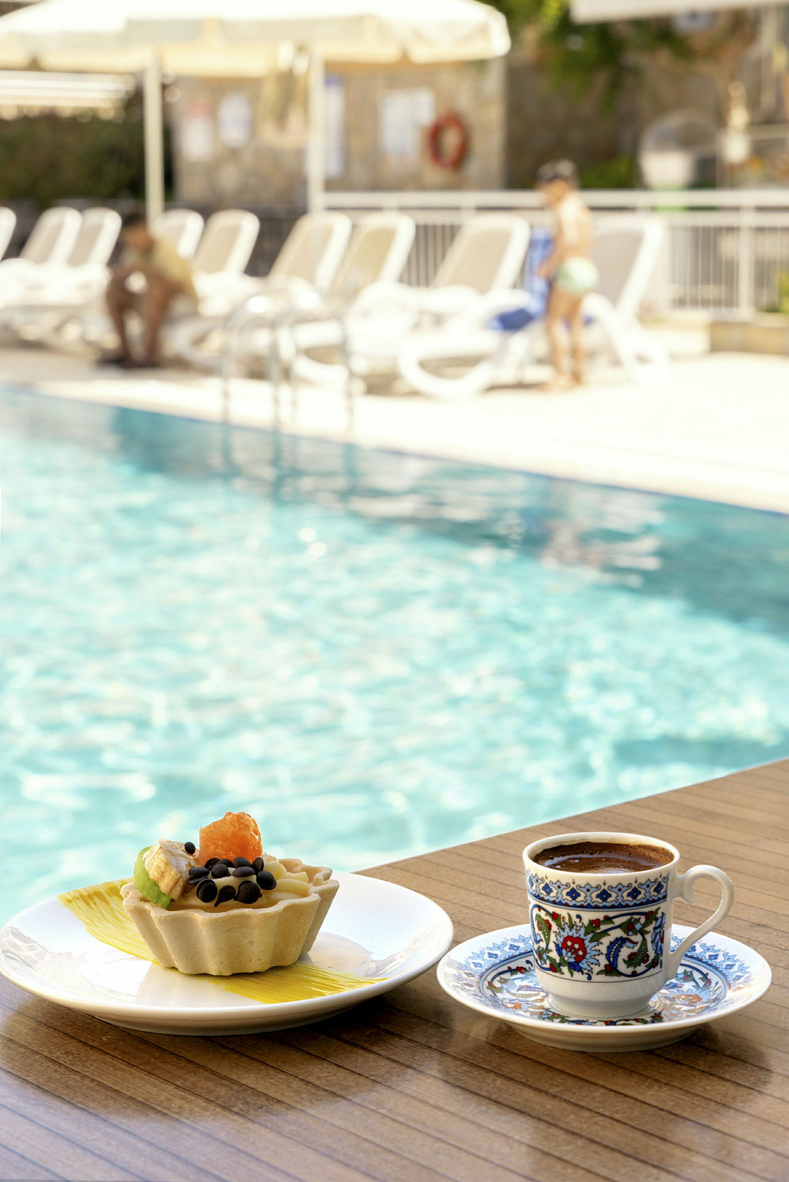 En kop kaffe og en dessert ved kanten af en pool. (AI-genereret tekst)
