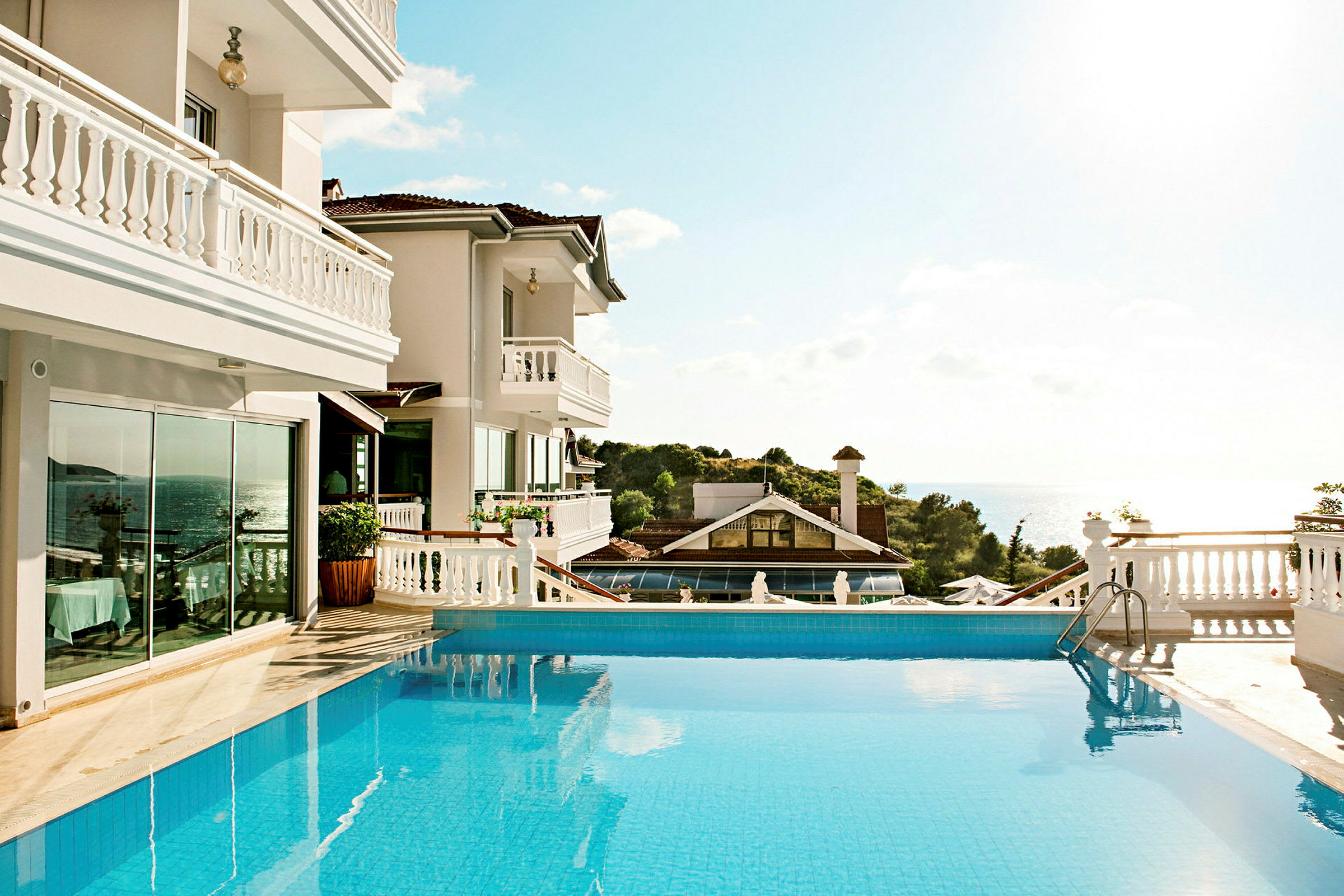 Hotel med solbeskinnet pool og udsigt over havet. (AI-genereret tekst)