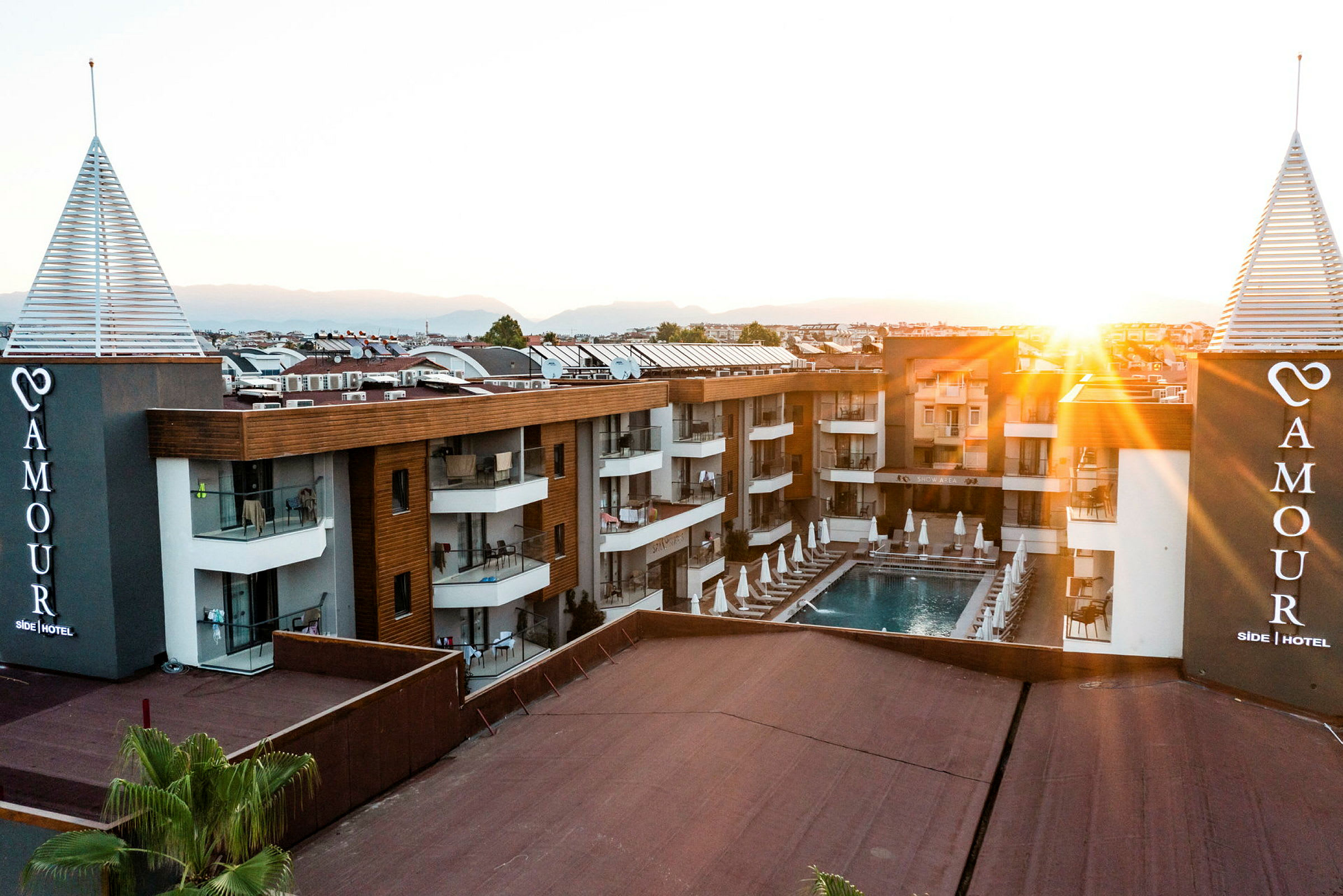 Hotelbygning med pool og liggestole ved solnedgang. (AI-genereret tekst)