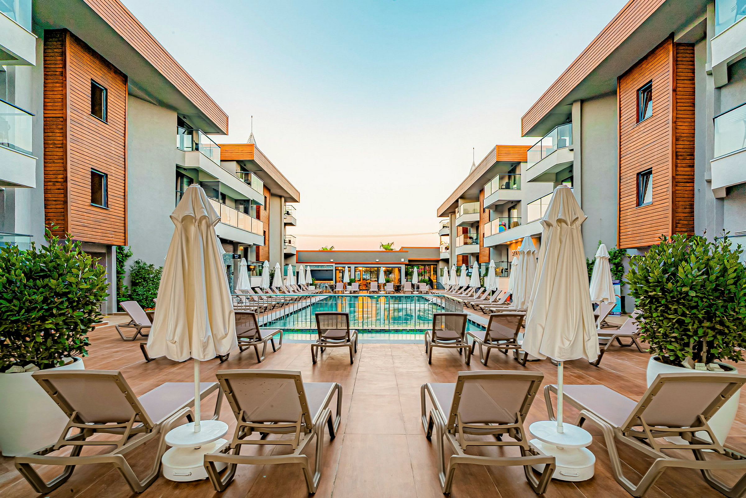 Hotelområde med en pool og liggestole omgivet af bygninger. (AI-genereret tekst)