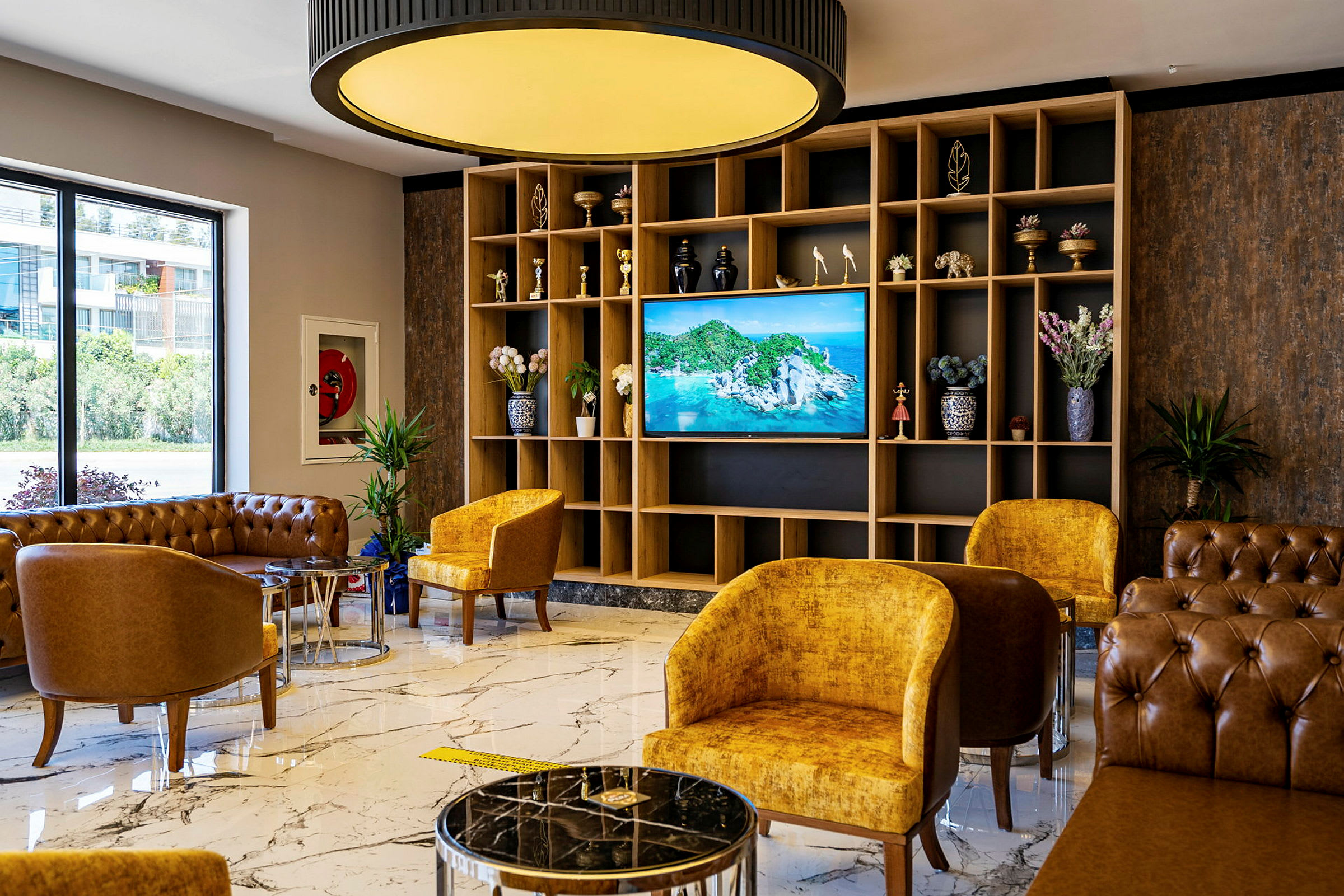 Hotellets lobby med siddepladser, marmorgulv og en TV med naturmotiv. (AI-genereret tekst)