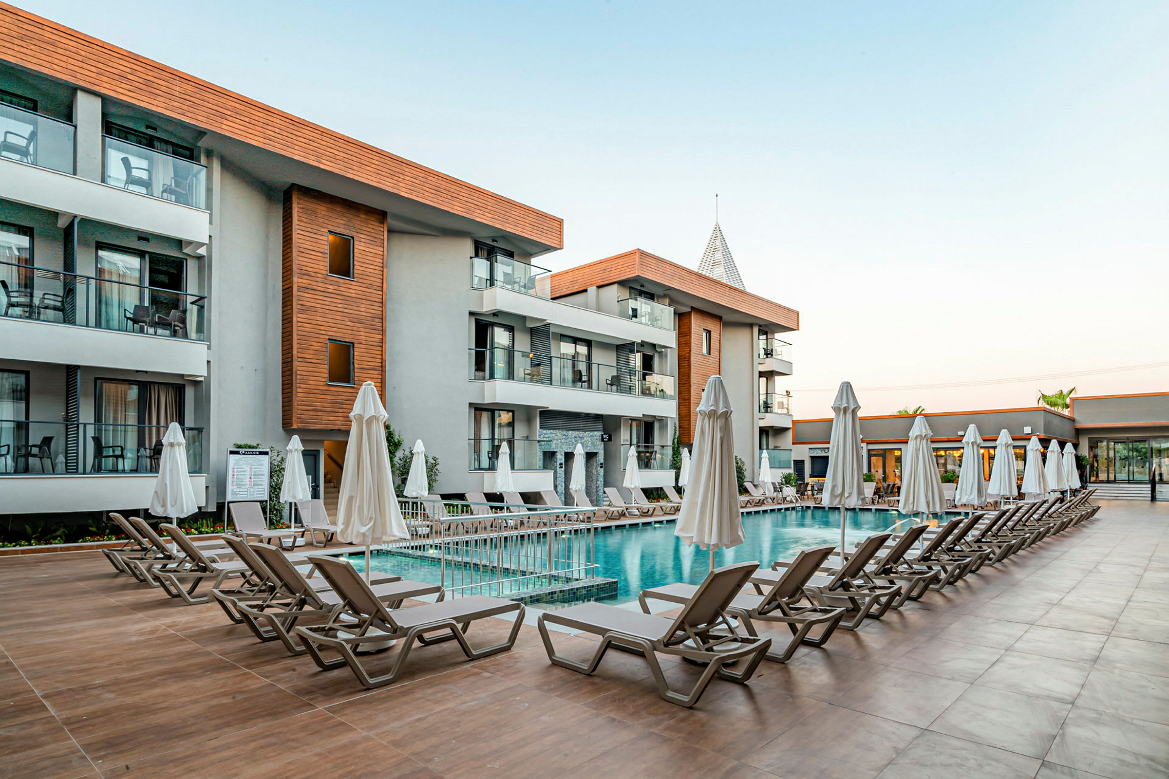 Udvendigt af et hotel med en pool og liggestole. (AI-genereret tekst)