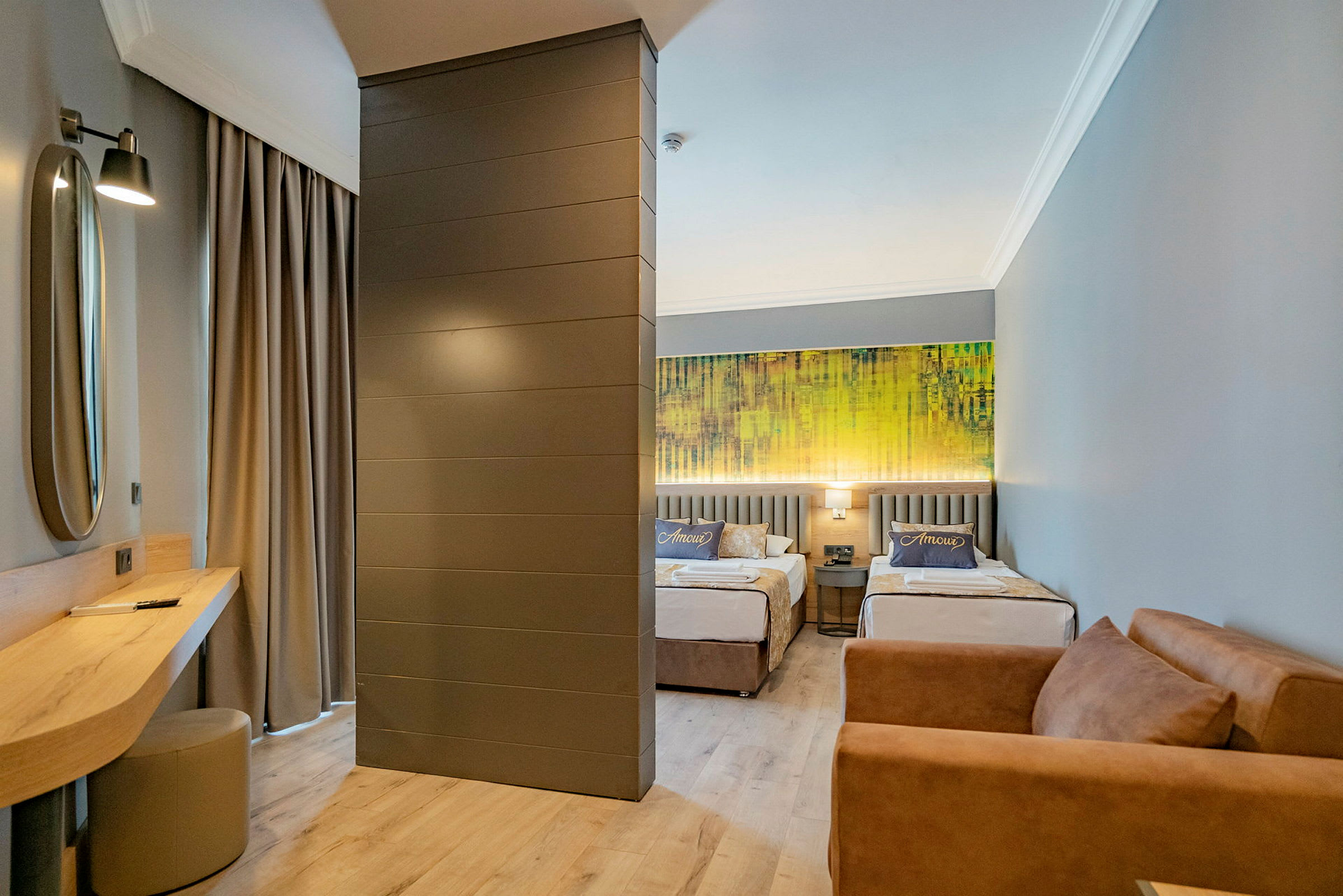 Hotelværelse med to enkeltsenge, en sofa og et skrivebord. (AI-genereret tekst)