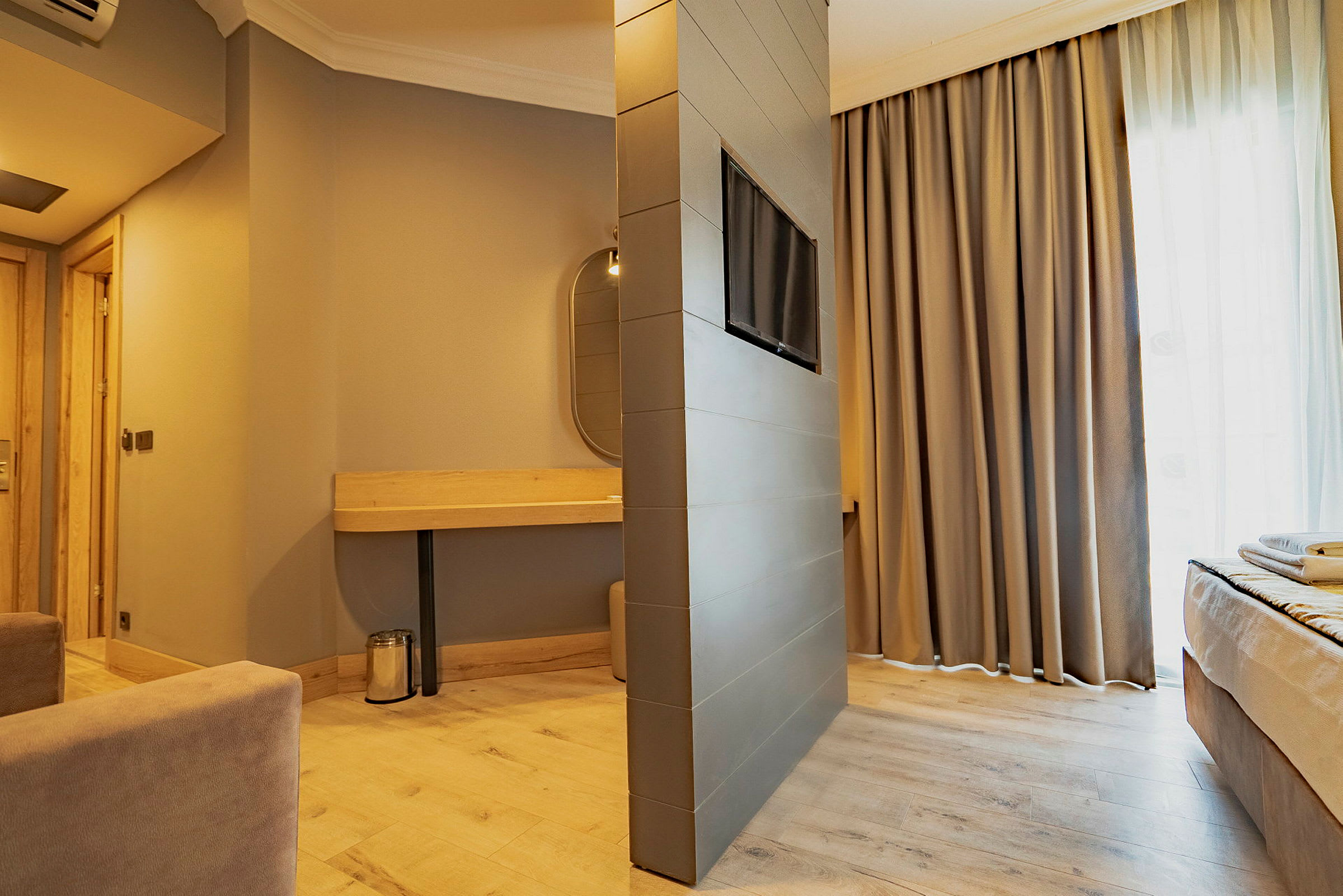Moderne hotelværelse med varm indretning, komfortable møbler og kombineret sofa- og sovemiljø. (AI-genereret tekst)