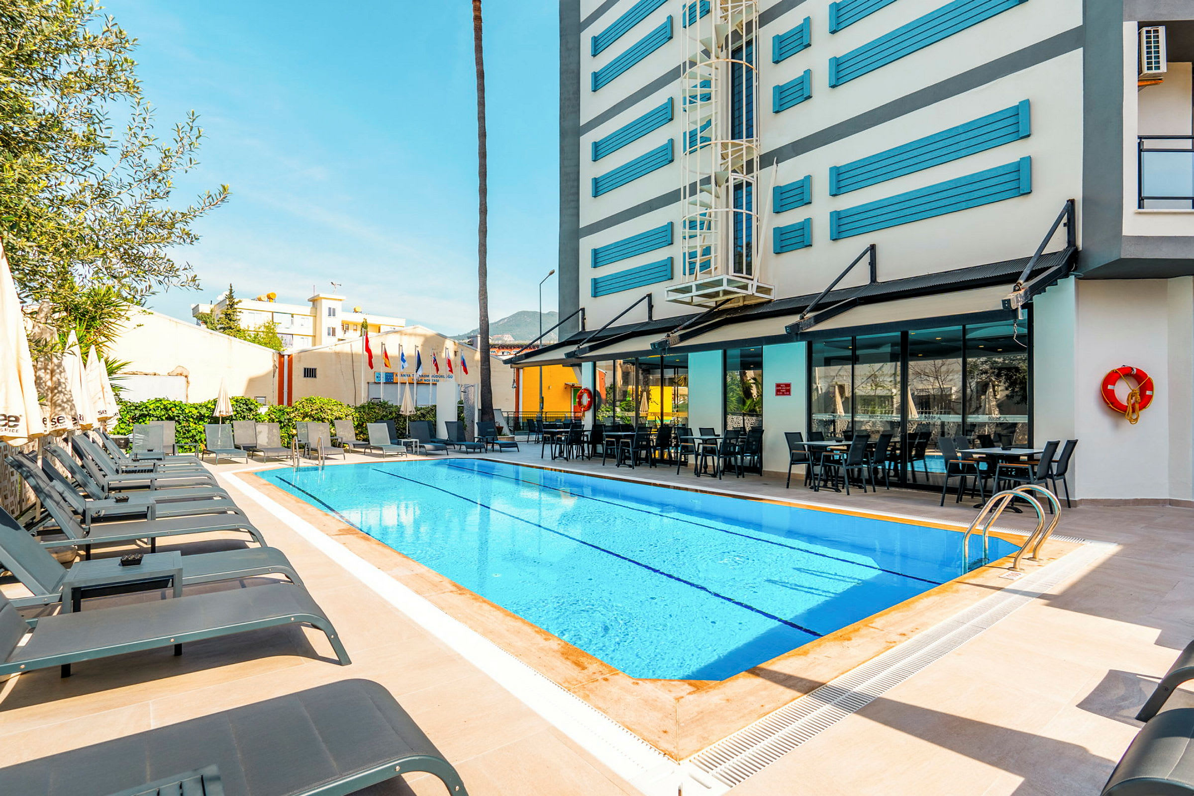 En udendørs pool med solsenge og et hotel i baggrunden. (AI-genereret tekst)