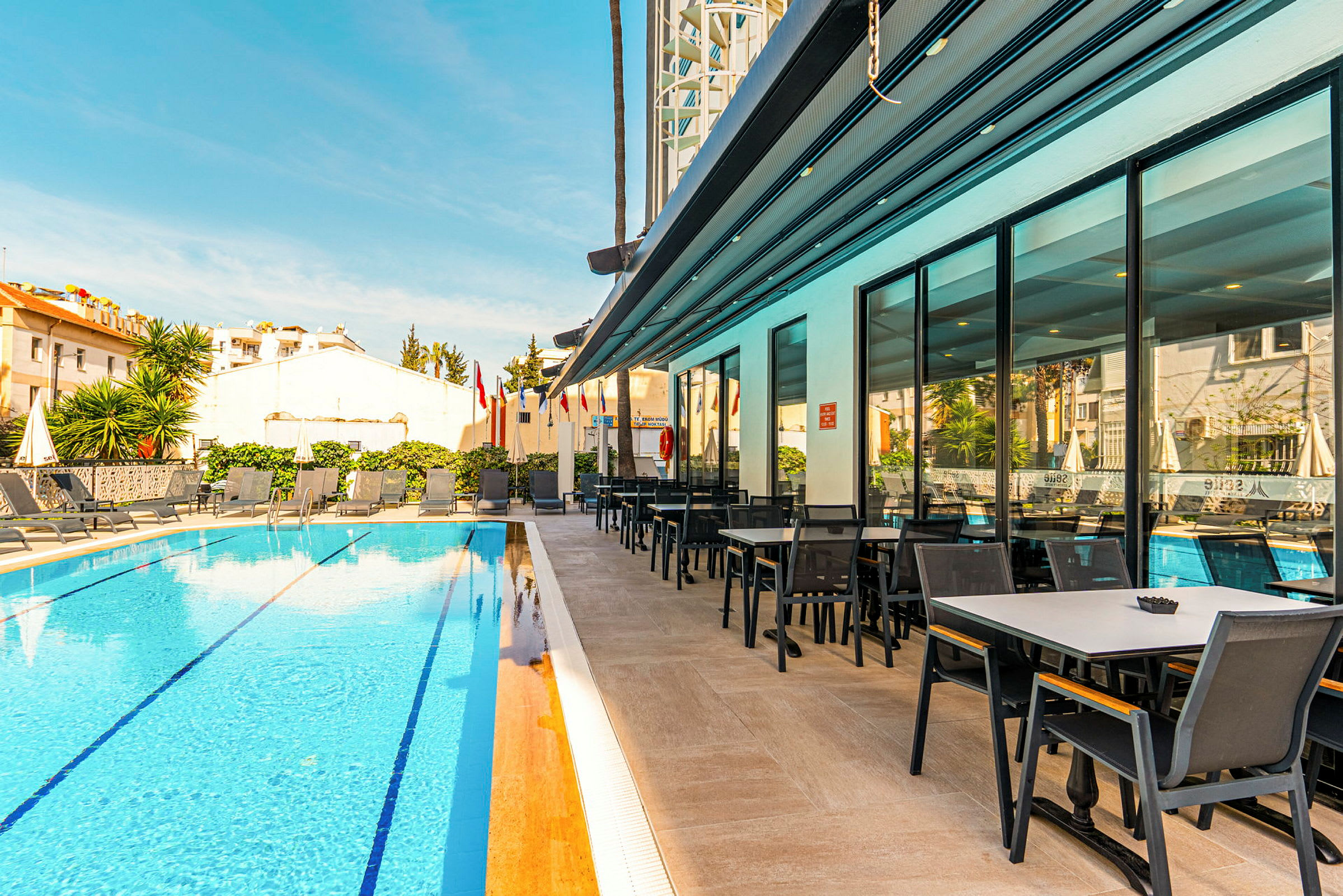 En hotelpool med liggestole og et tilstødende spiseområde. (AI-genereret tekst)
