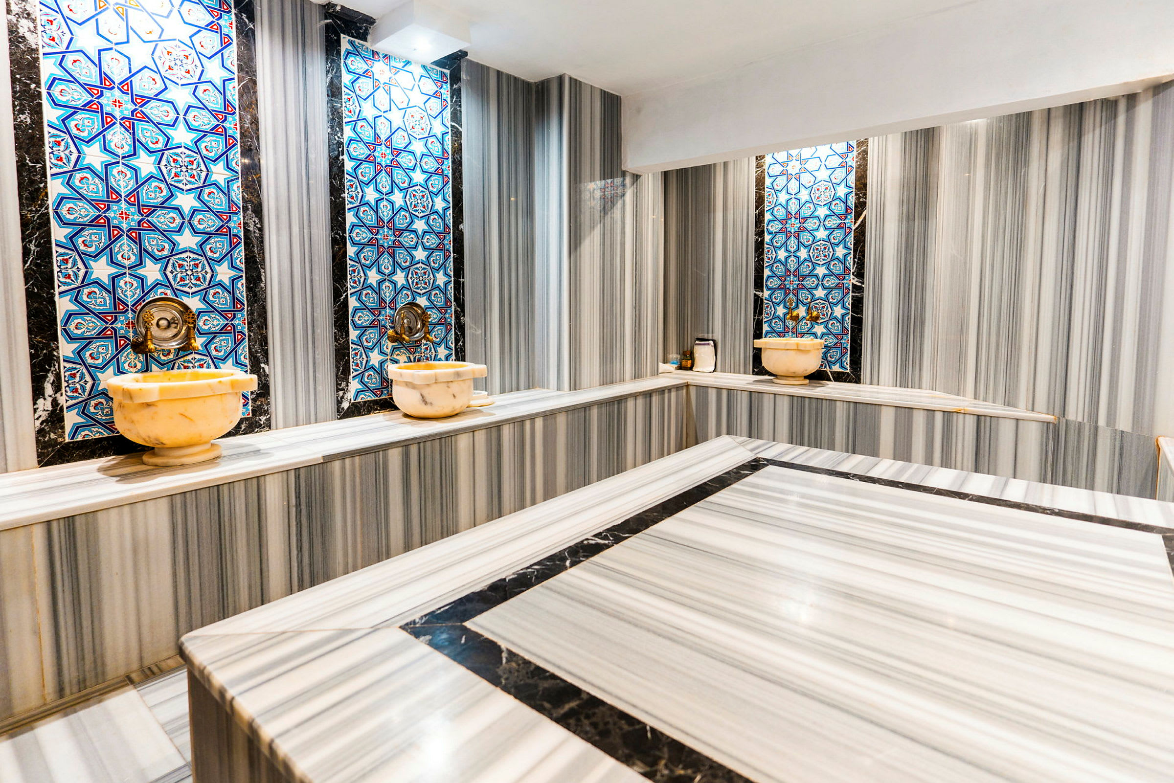 Traditionel hamam med marmaroverflader og blå mosaik på væggene. (AI-genereret tekst)