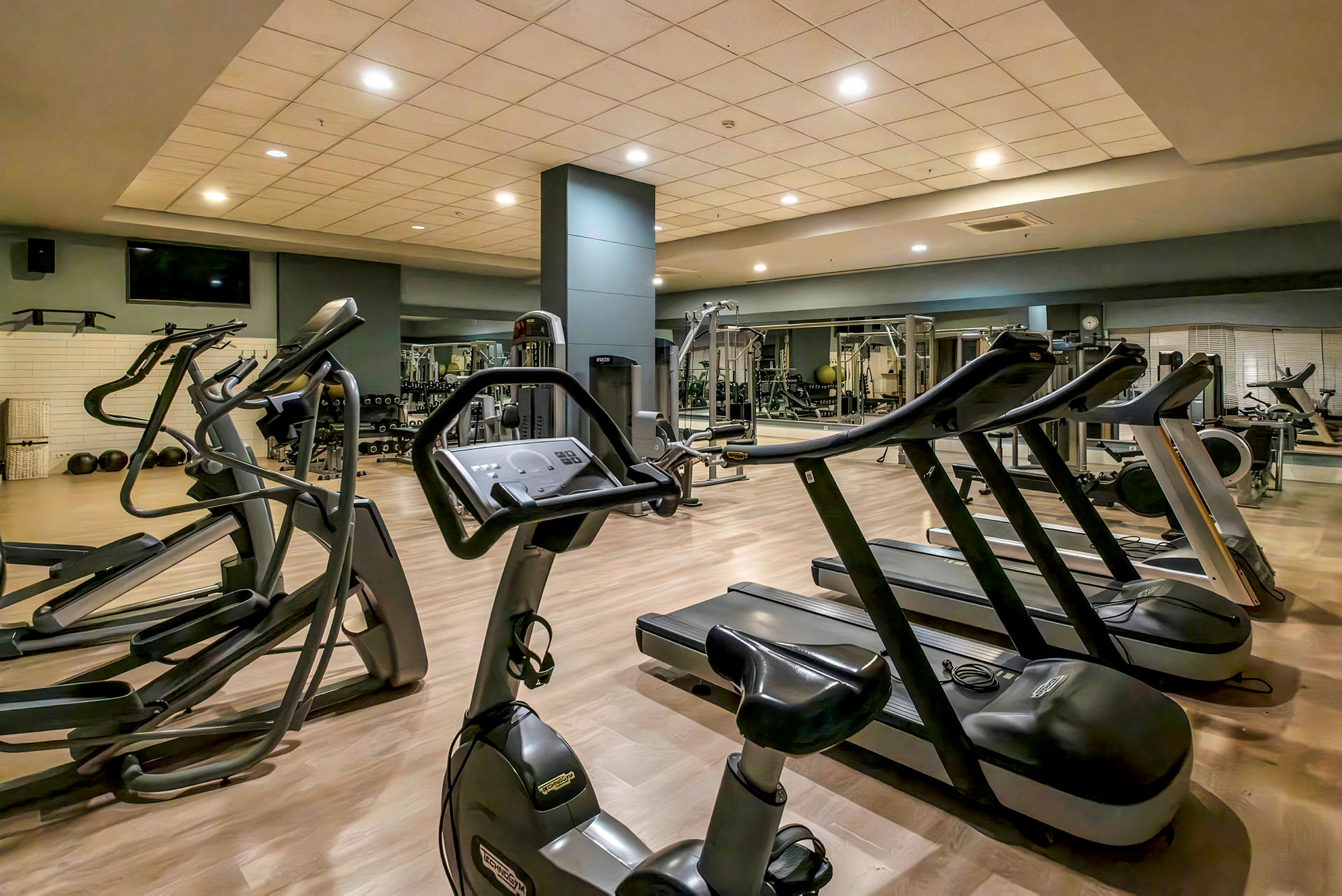 Et fitnesscenter med løbebånd, træningscykel og andre træningsmaskiner. (AI-genereret tekst)