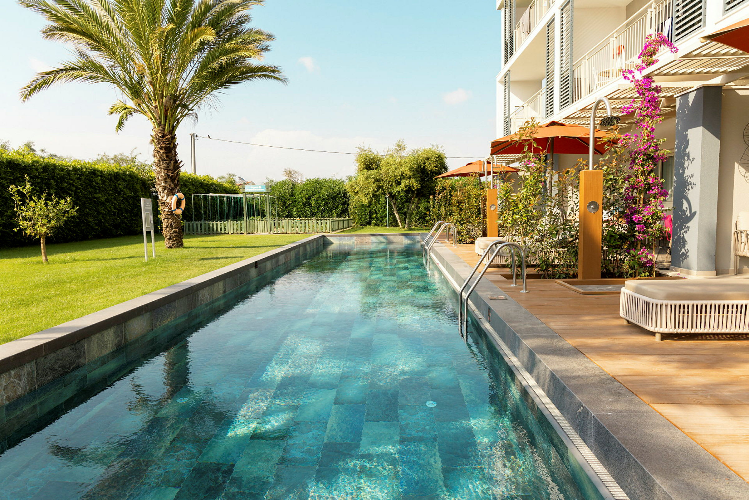 En lang smal pool omgivet af grønne områder og en moderne bolig. (AI-genereret tekst)