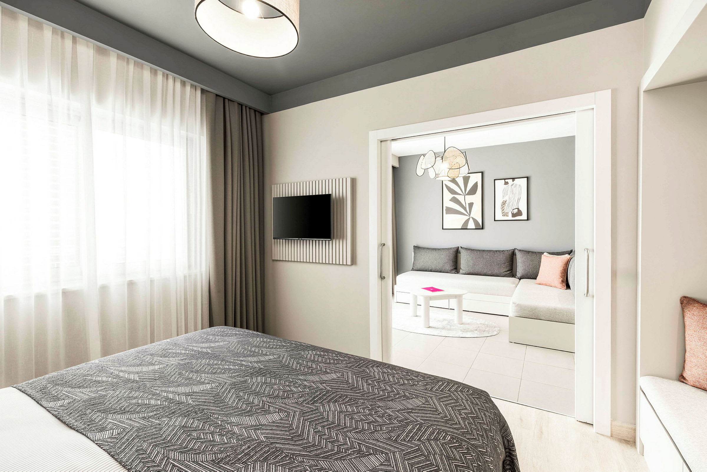 Hotelværelse med en seng i forgrunden, et tv på væggen og en separat siddegruppe med sofa og bord. (AI-genereret tekst)