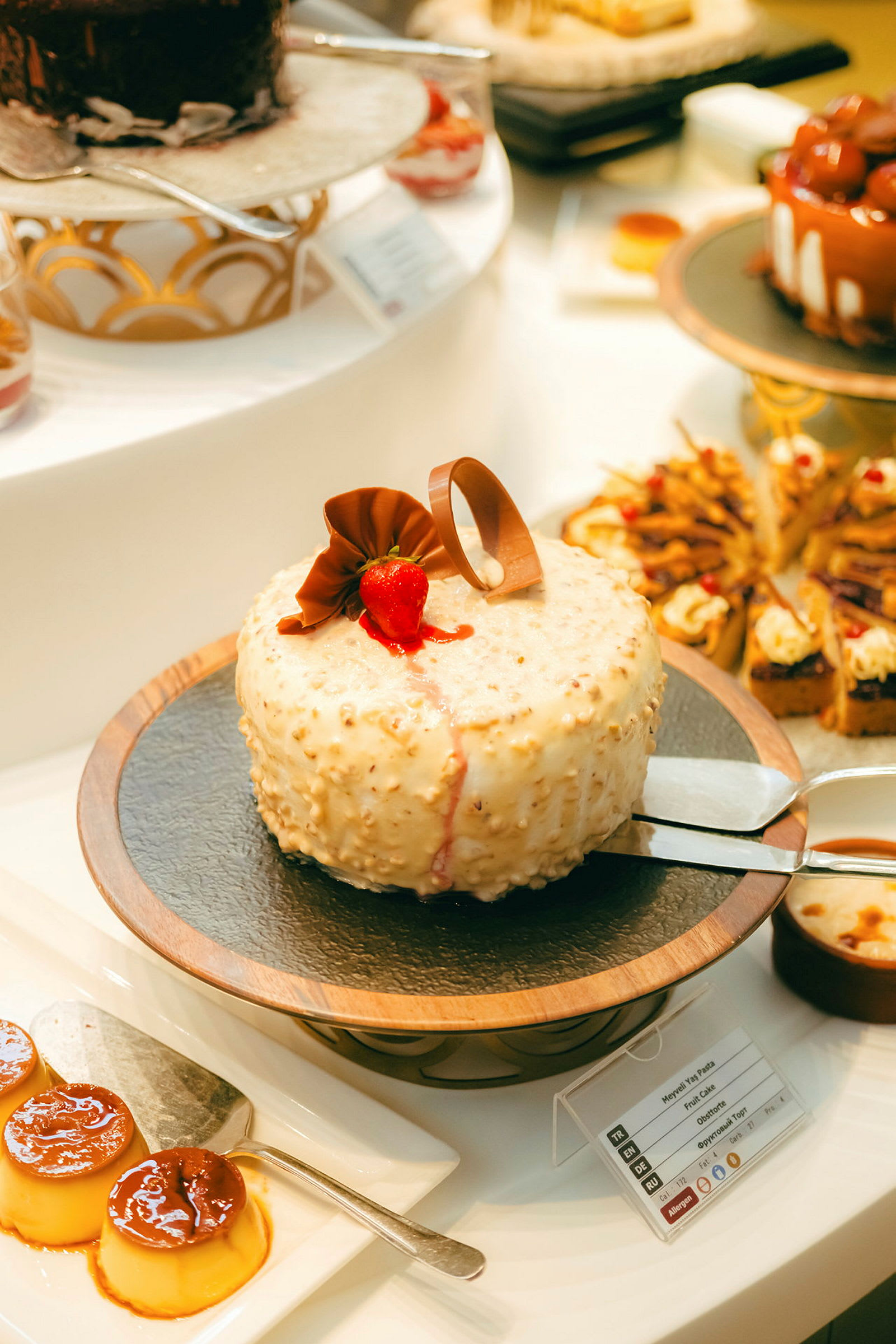 En dessertbuffet med forskellige bagværk, herunder en flødekage med chokoladepynt og jordbær. (AI-genereret tekst)