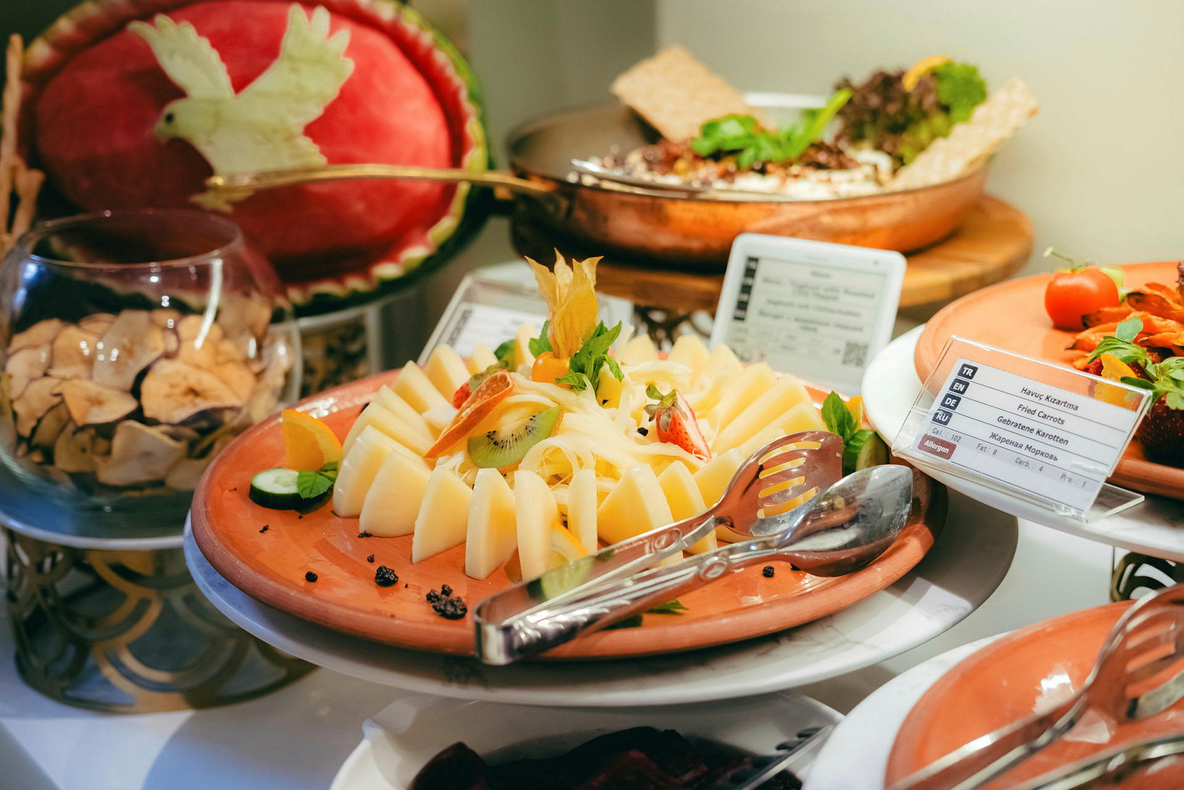 En buffet med ost dekoreret med frugt og grøntsager. (AI-genereret tekst)