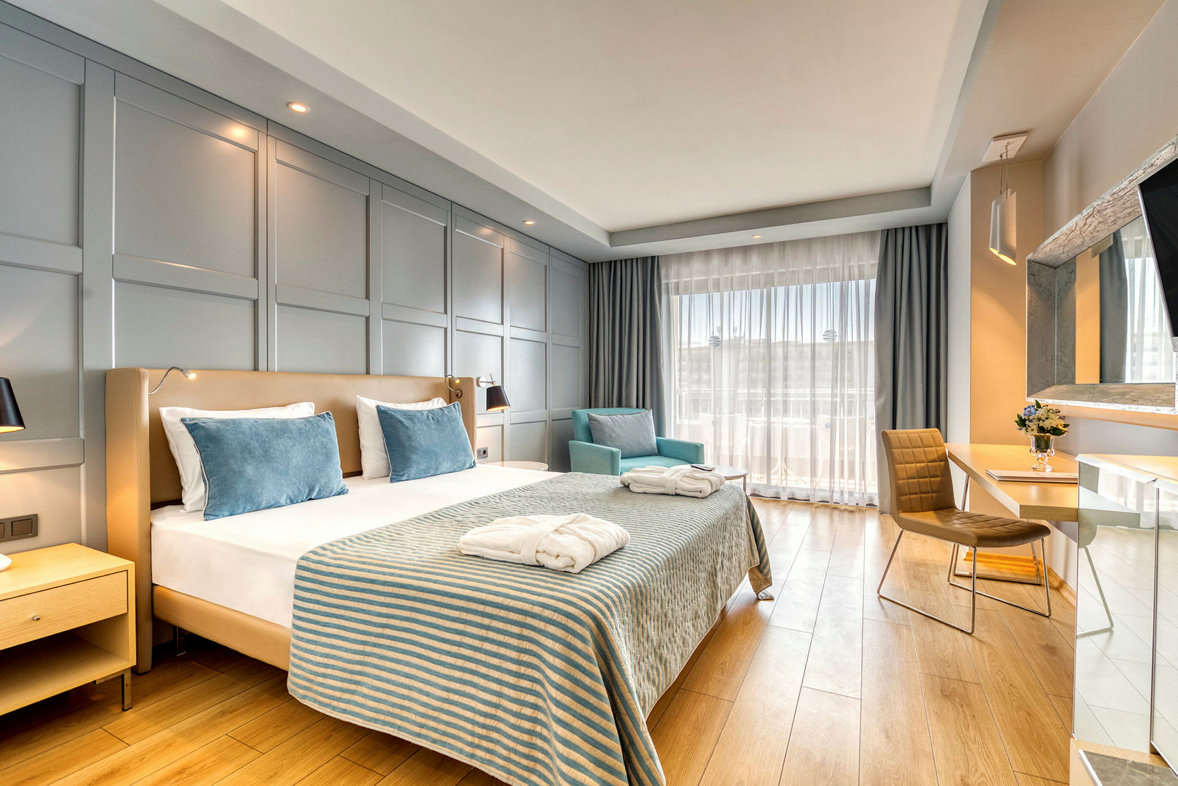 Hotelværelse med en dobbeltseng, to lænestole og et skrivebord. (AI-genereret tekst)