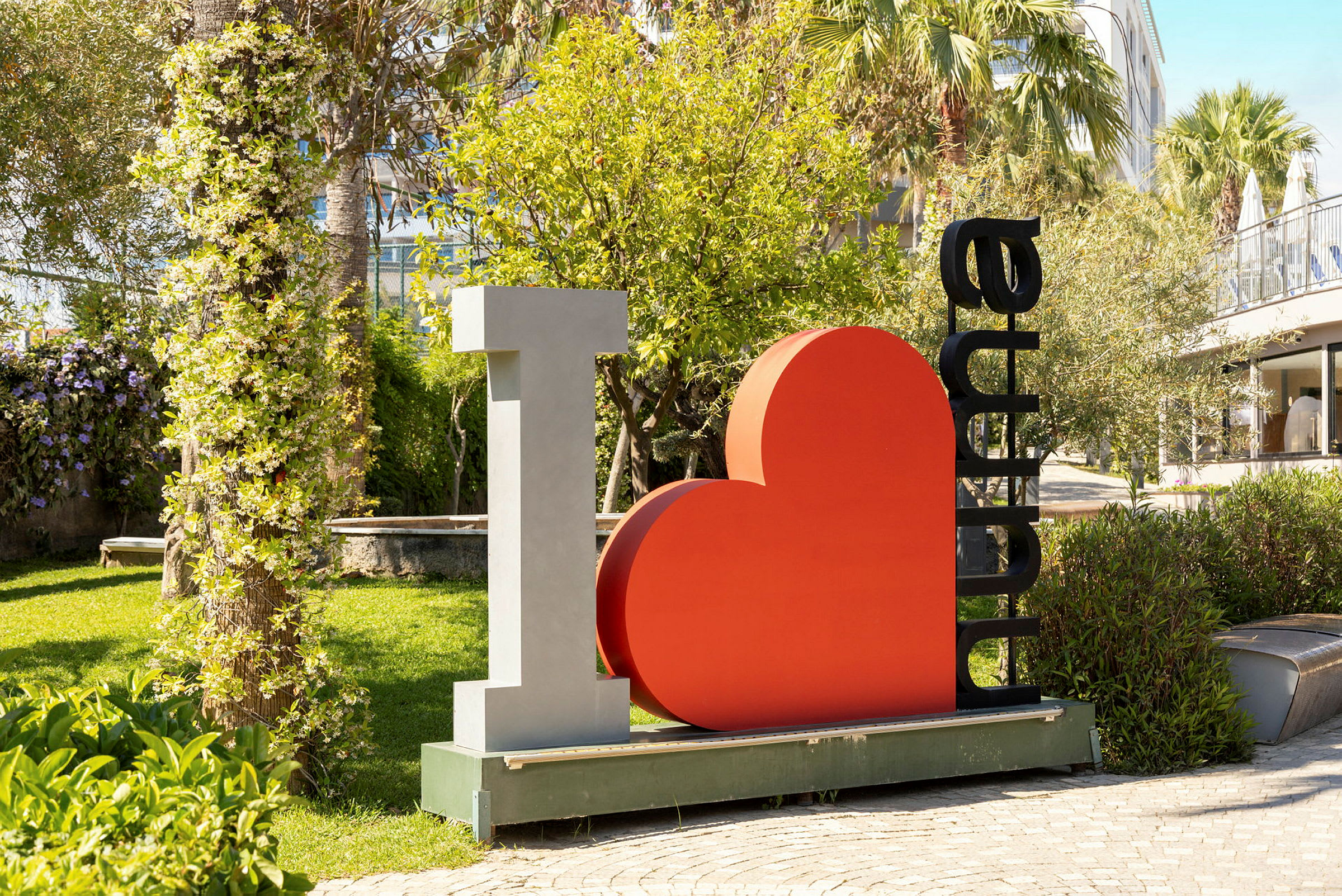 Skulpturen viser teksten "I ♡ Alanya" omgivet af en frodig have. (AI-genereret tekst)