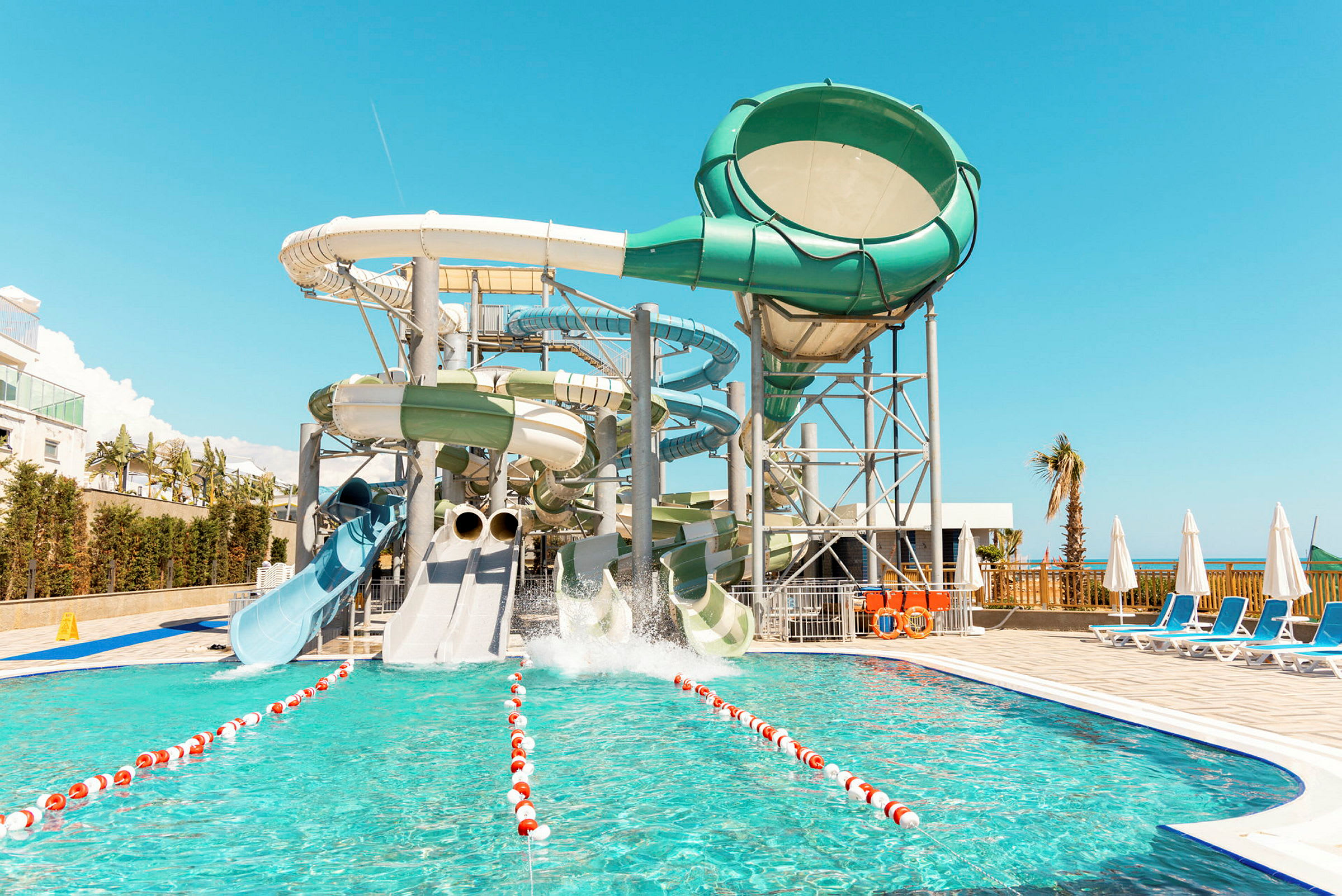 Billedet viser en vandpark med flere store vandrutsjebaner og en pool i forgrunden. (AI-genereret tekst)