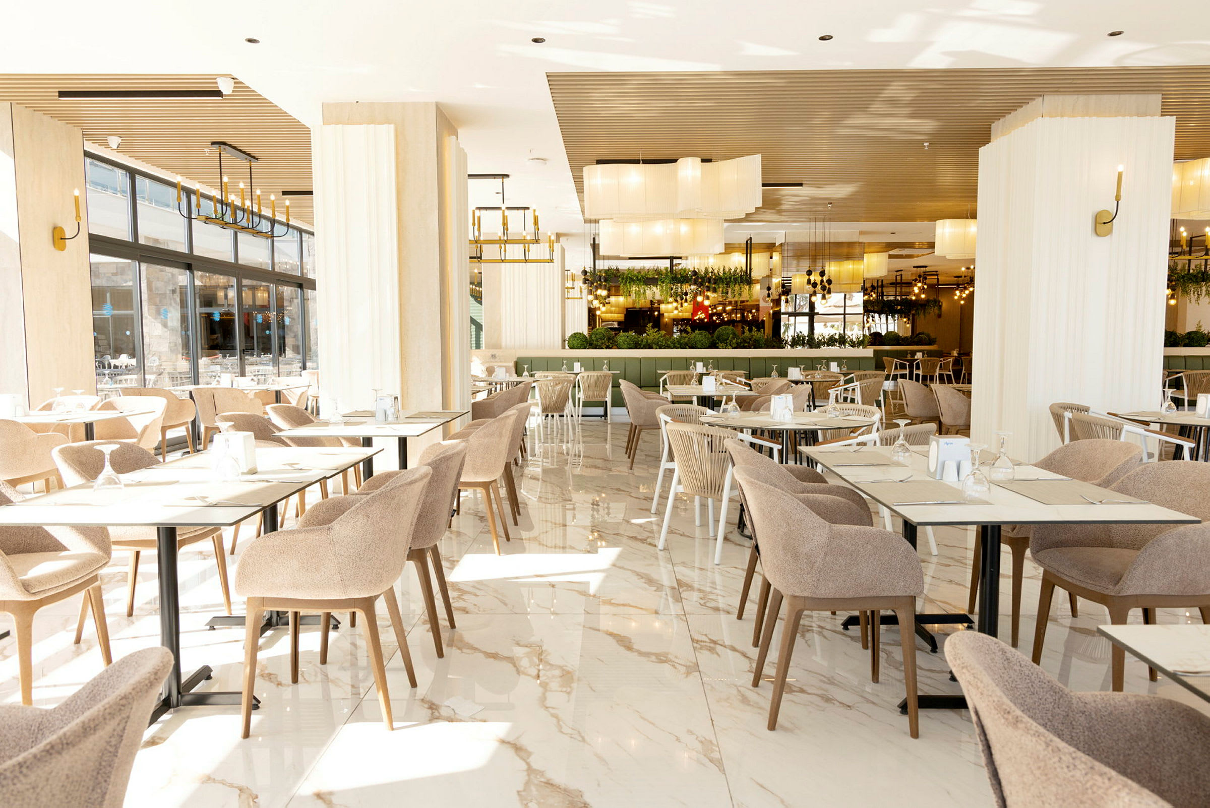 Interiør af en rummelig og lys restaurant med borde og stole. (AI-genereret tekst)