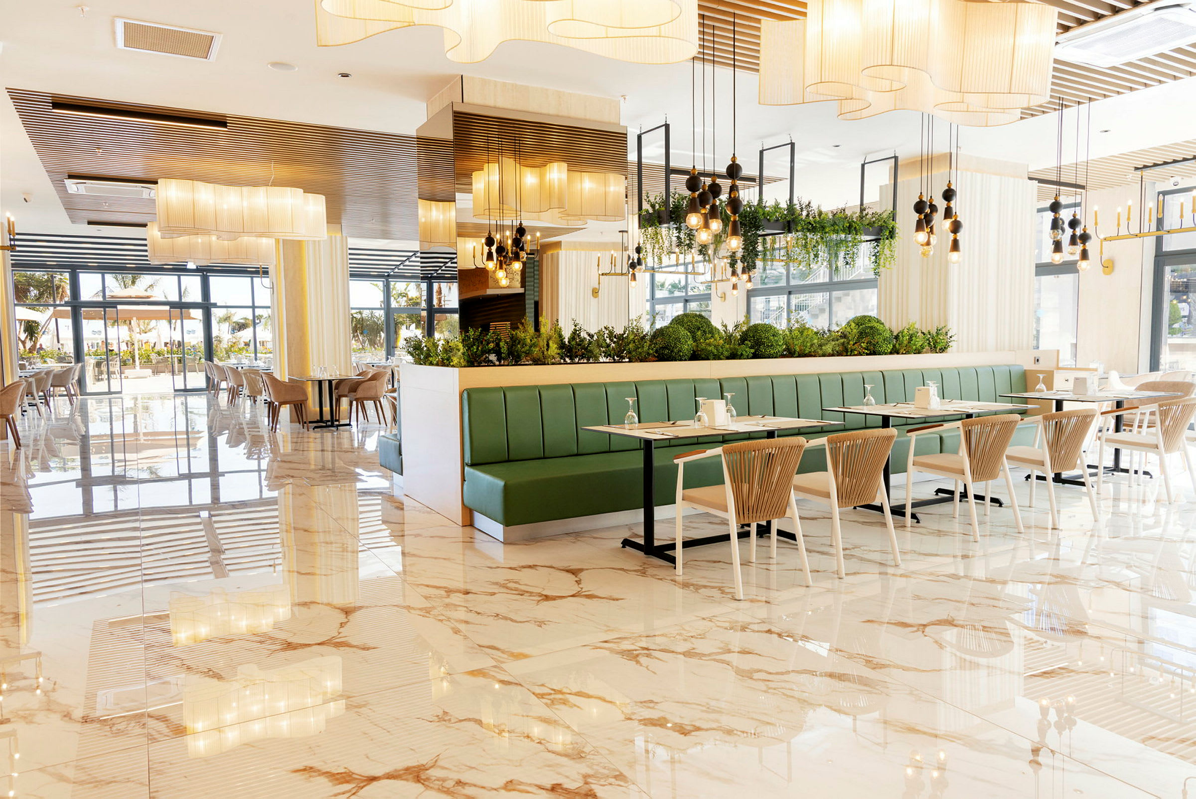 En lys restaurant med marmorgulv, grønne siddebænke og moderne indrettede borde og stole. (AI-genereret tekst)