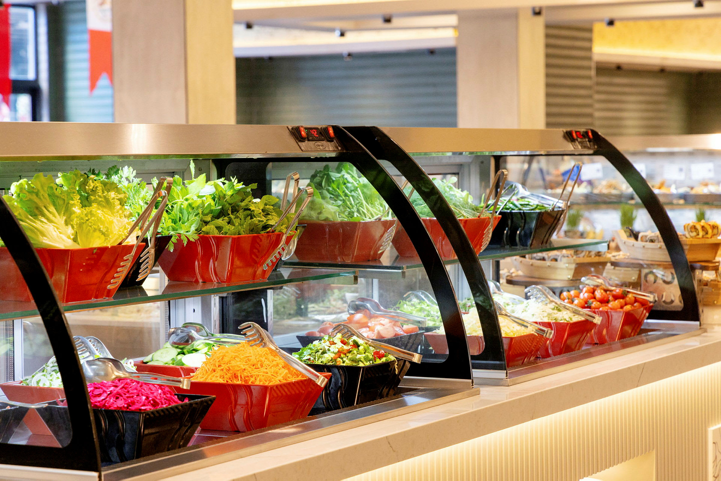 En salatbuffet med forskellige grøntsager og salatingredienser, arrangeret i glas- og plastikskåle. (AI-genereret tekst)