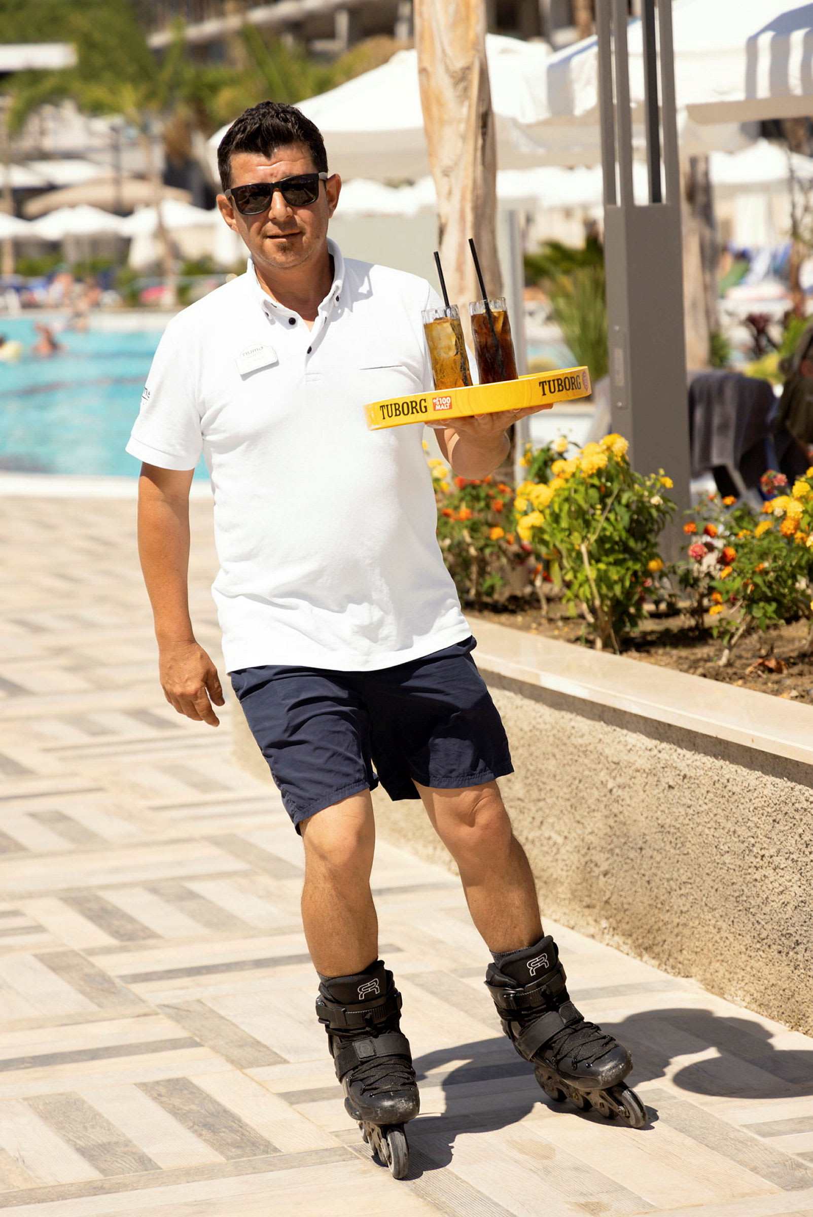En person på rulleskøjter serverer drikke ved en pool. (AI-genereret tekst)