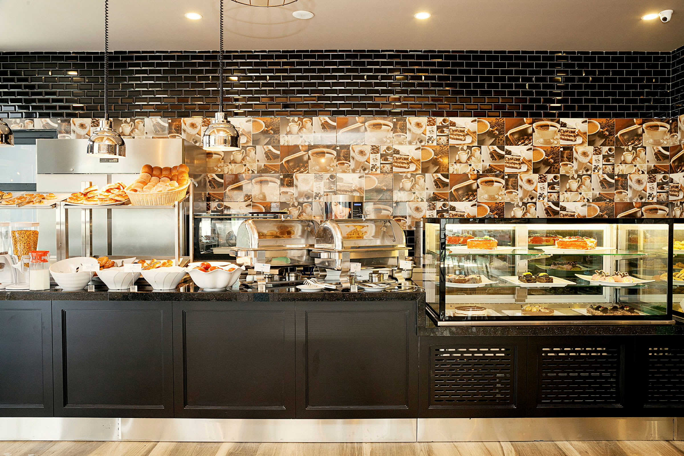 Billedet viser en morgenmadsbuffet med brød, bagværk og serveringsstationer opstillet på et sort bord. (AI-genereret tekst)
