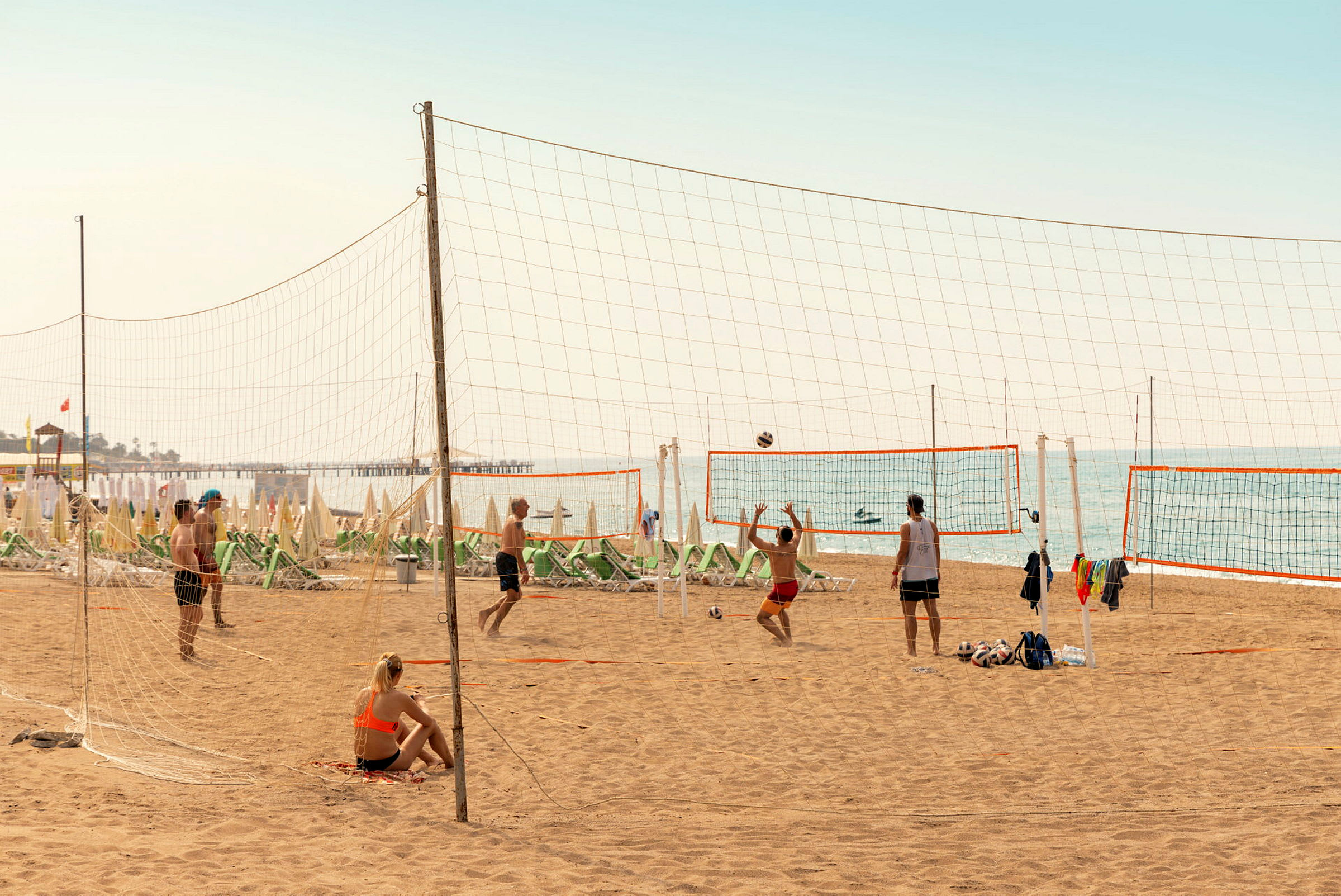 Personer spiller volleyball på en sandstrand. (AI-genereret tekst)