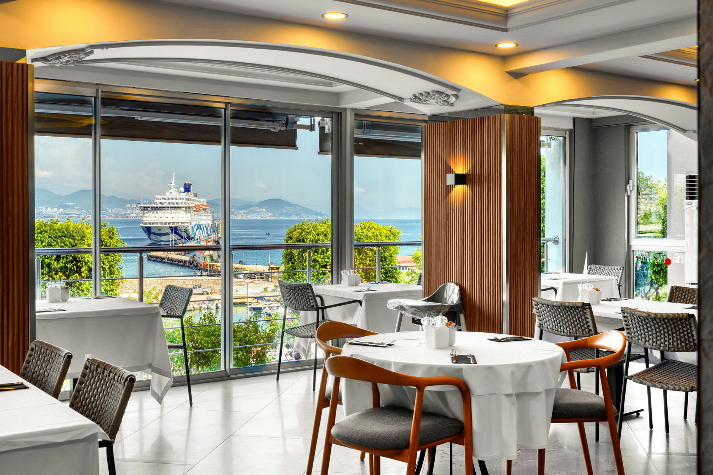Restaurant med udsigt over et krydstogtskib ved en havn. (AI-genereret tekst)