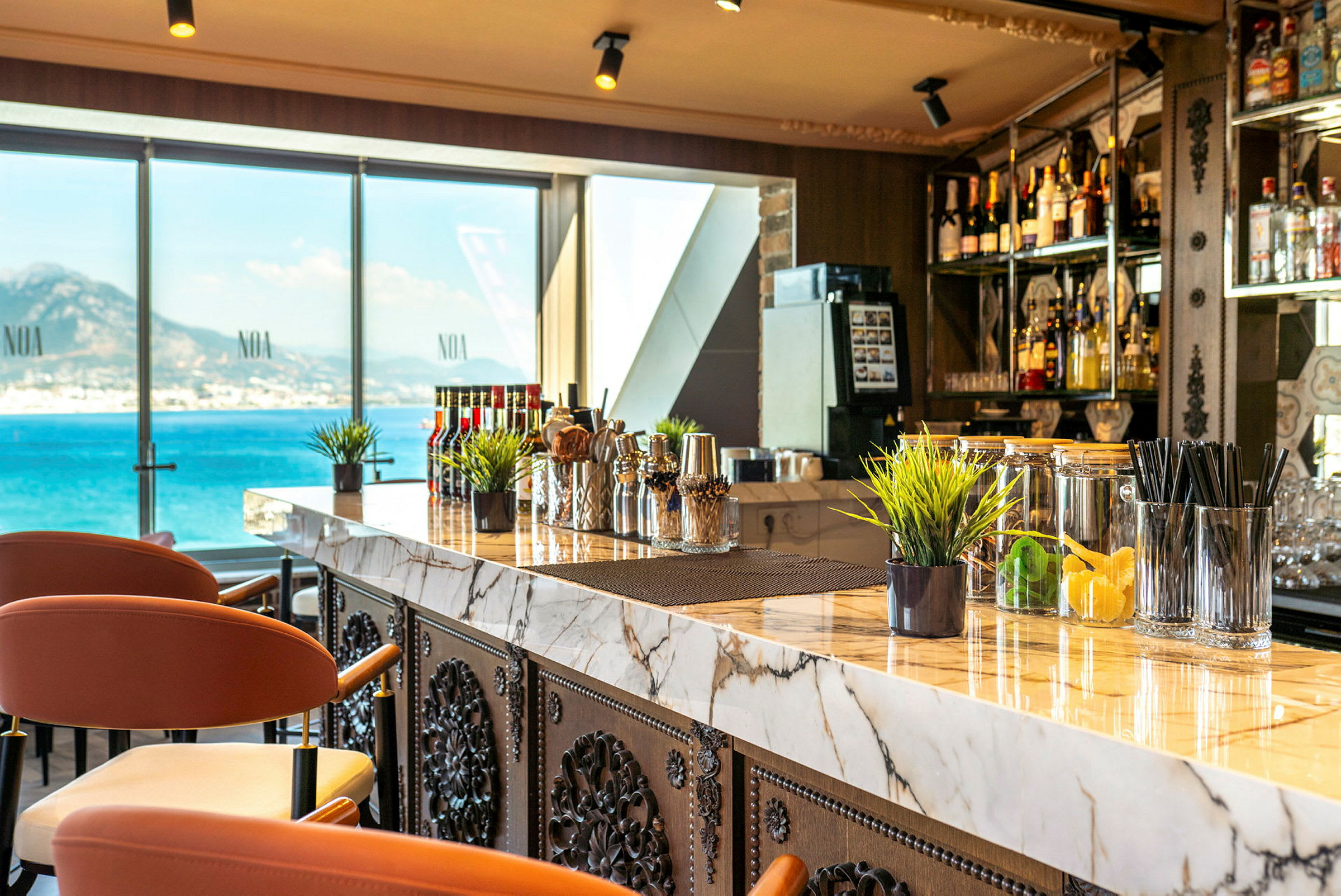 En moderne bar med marmorbord og stole samt udsigt over havet gennem store vinduer. (AI-genereret tekst)