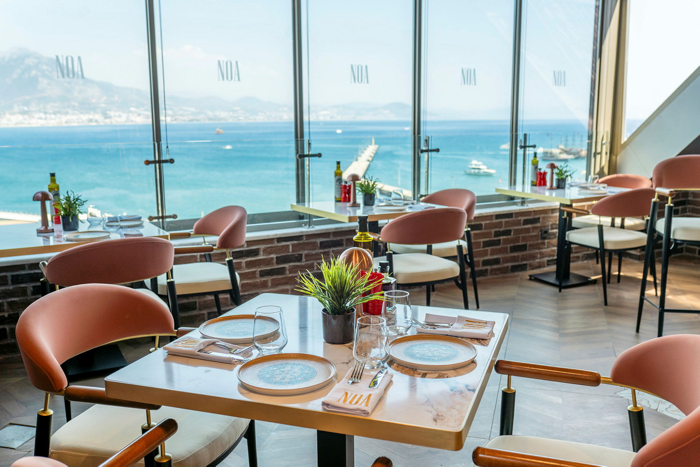 Restaurant med moderne møbler og udsigt over havet gennem store vinduer. (AI-genereret tekst)