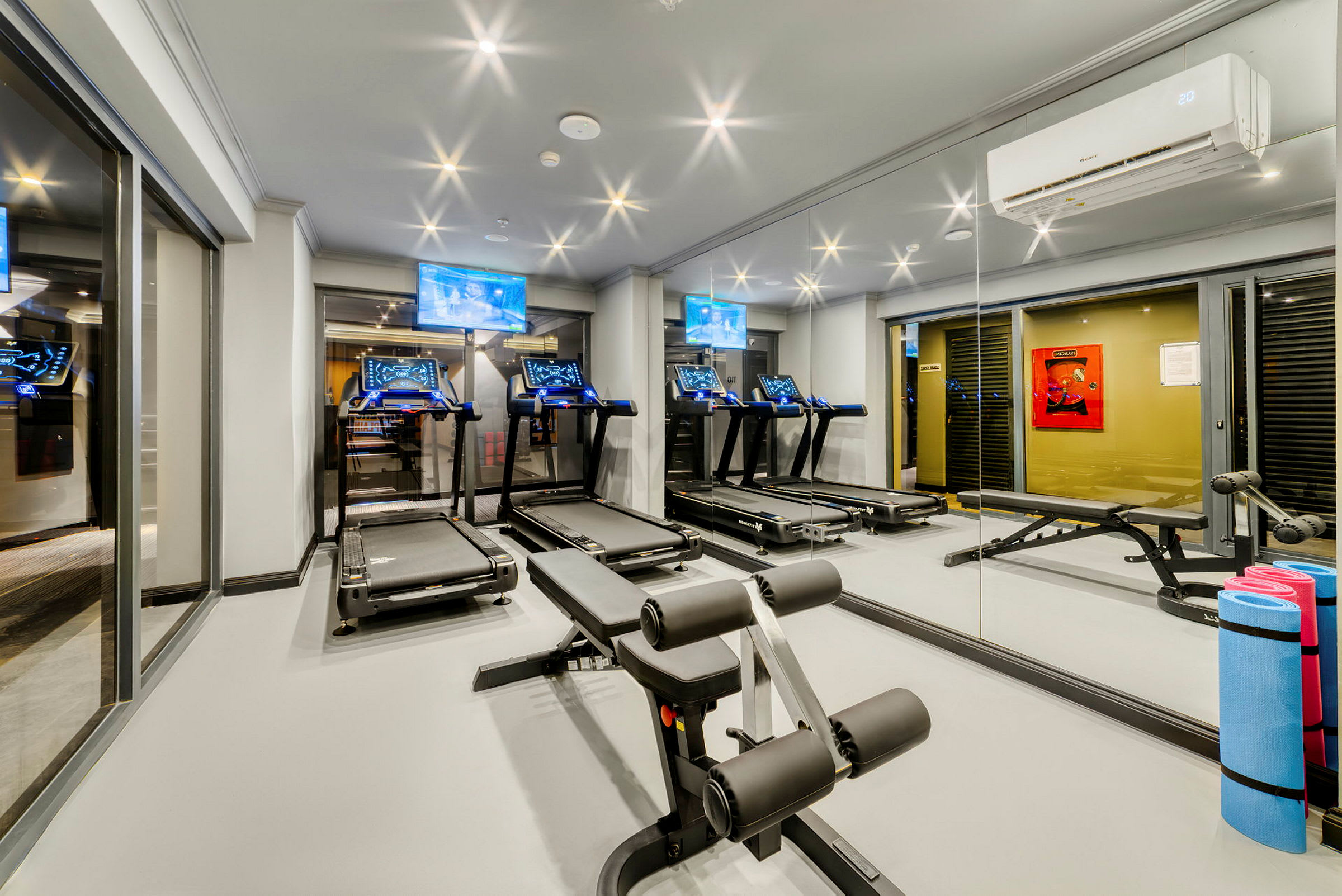 Et fitnesscenter med løbebånd, træningsbænk og andre træningsredskaber. (AI-genereret tekst)