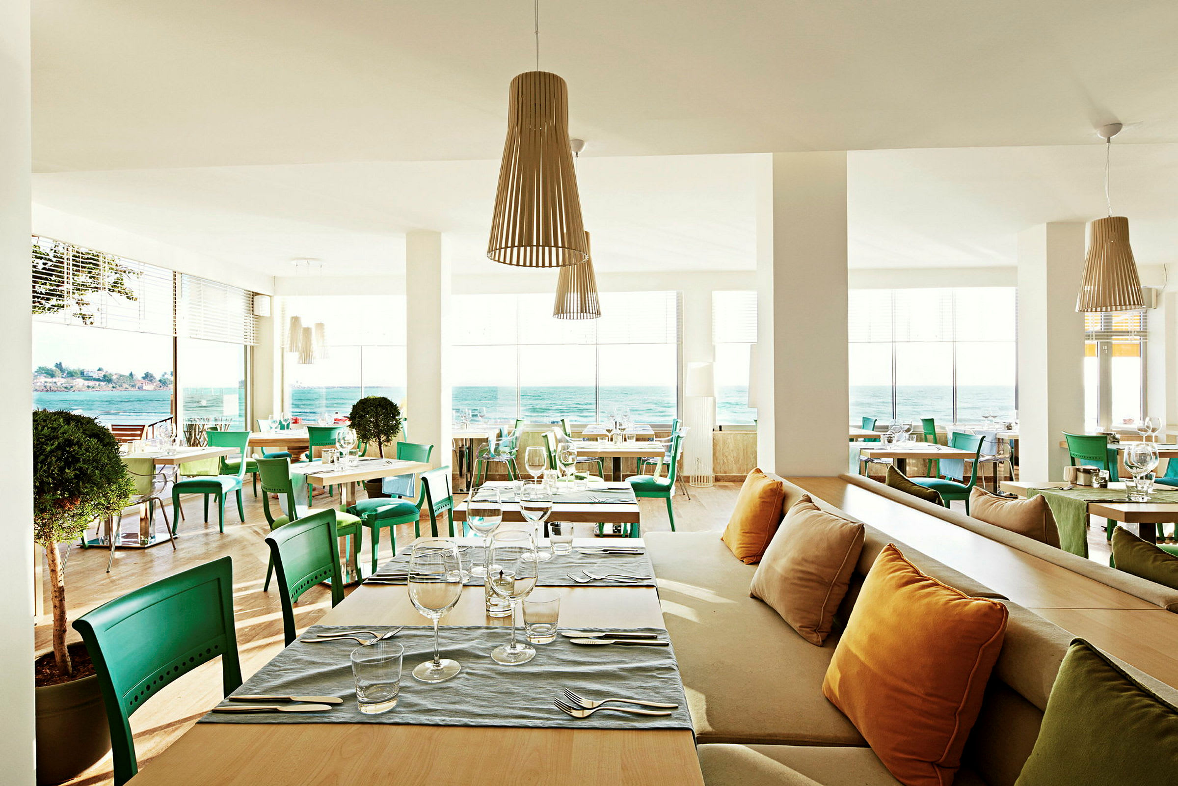 Moderne restaurant med havudsigt og grønne stole. (AI-genereret tekst)