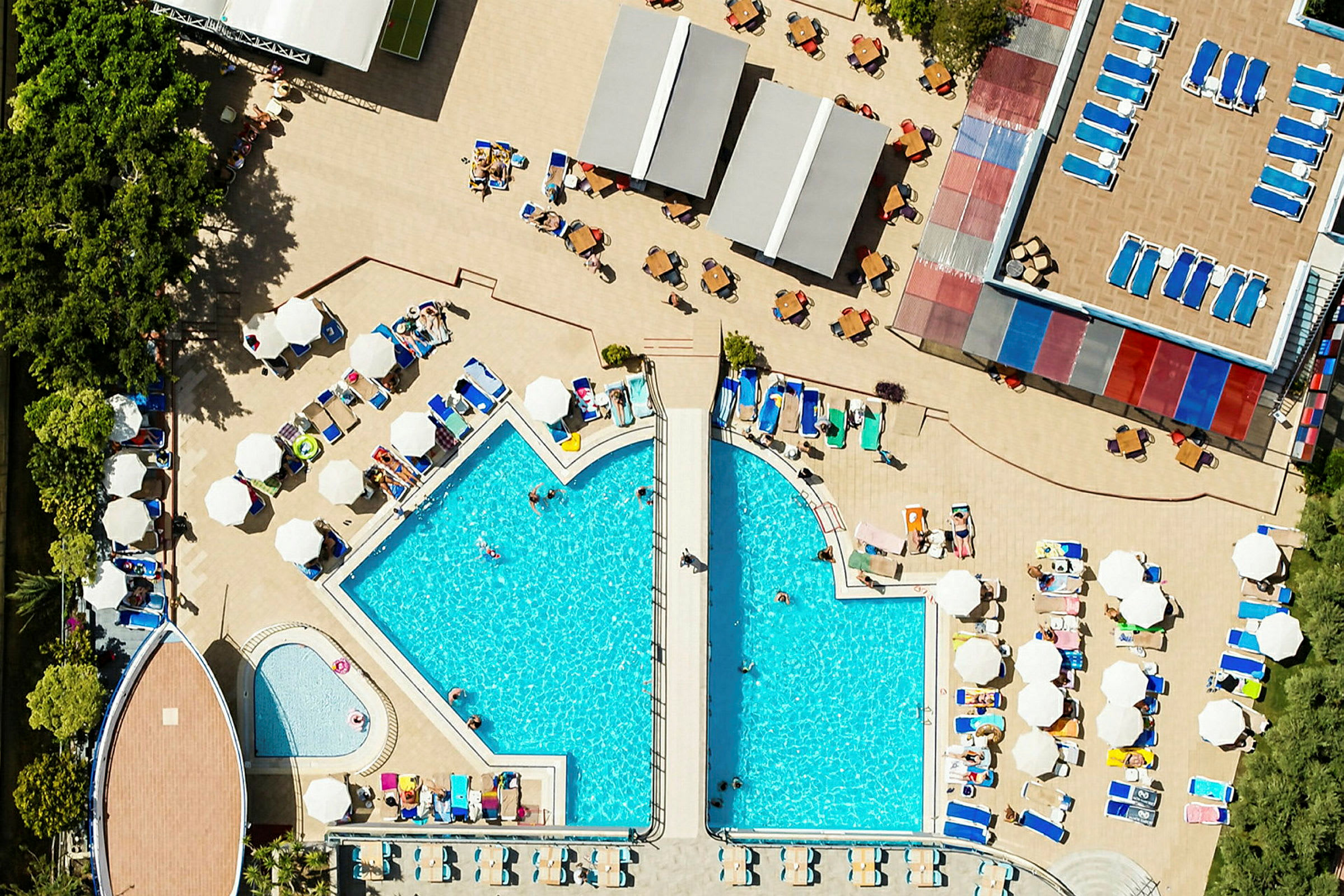 Et overblik af en hotelpool med omkringliggende liggestole og parasoller. (AI-genereret tekst)