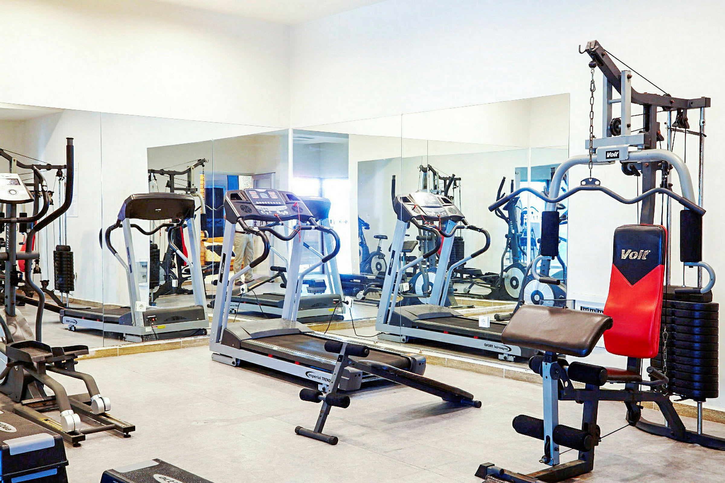 Fitnessrum med træningsmaskiner, herunder løbebånd og styrketræningsudstyr. (AI-genereret tekst)