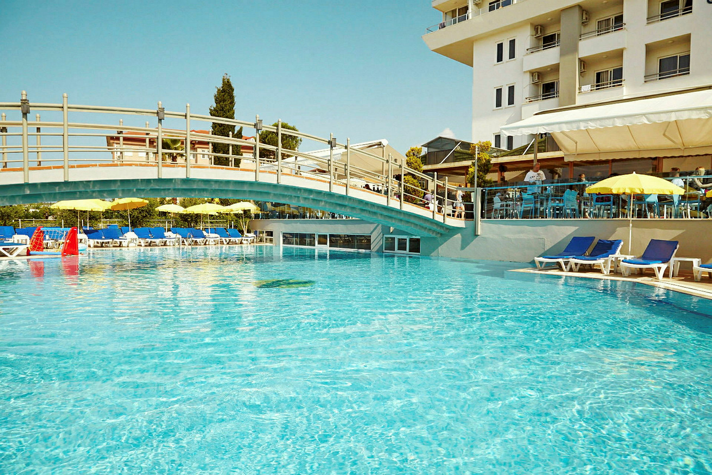 En udendørs pool med liggestole og parasoller ved et hotel. (AI-genereret tekst)