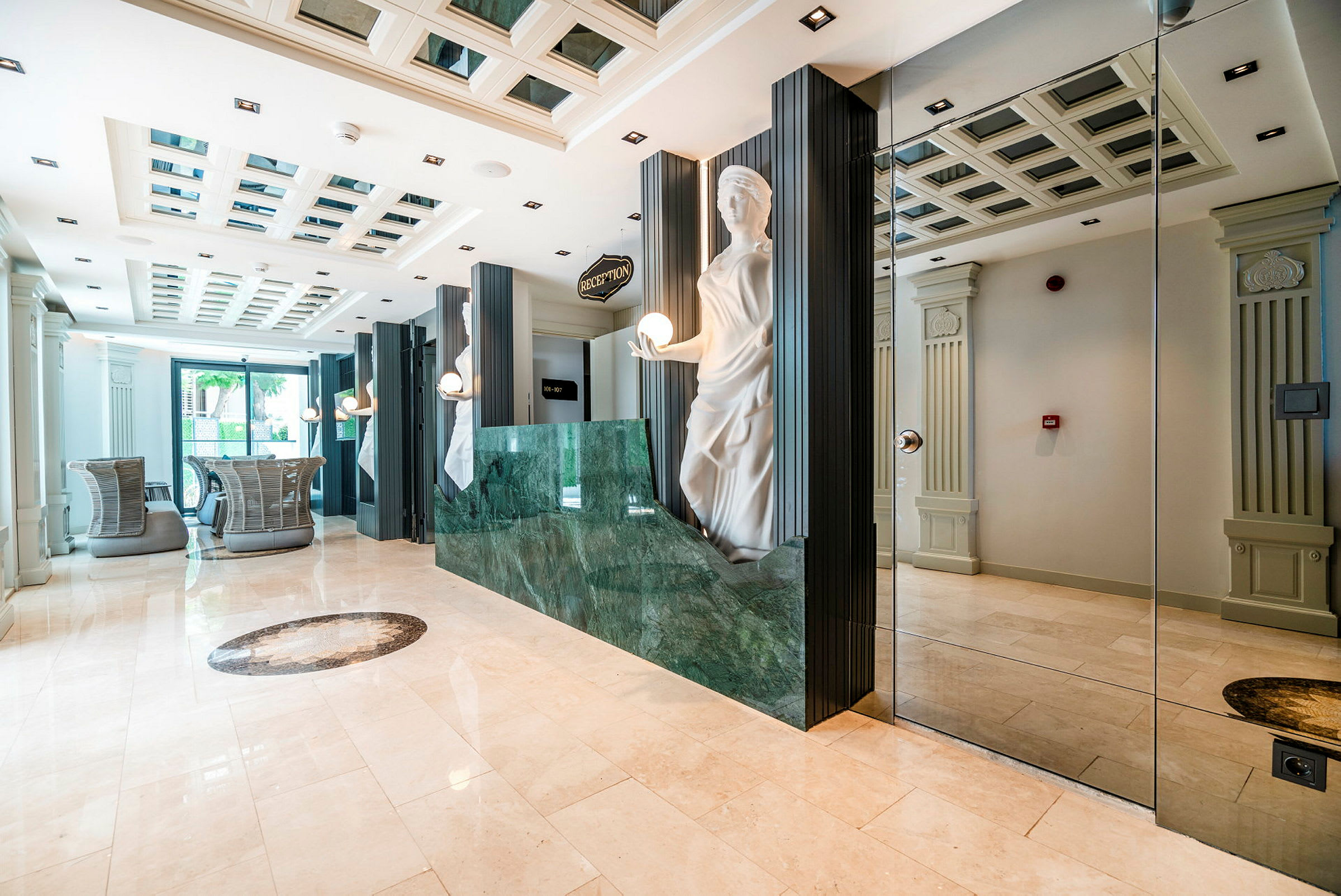 Et hotelreceptionsområde med marmorgulv, en grøn receptionsdisk og en dekorativ statue ved siden af. (AI-genereret tekst)