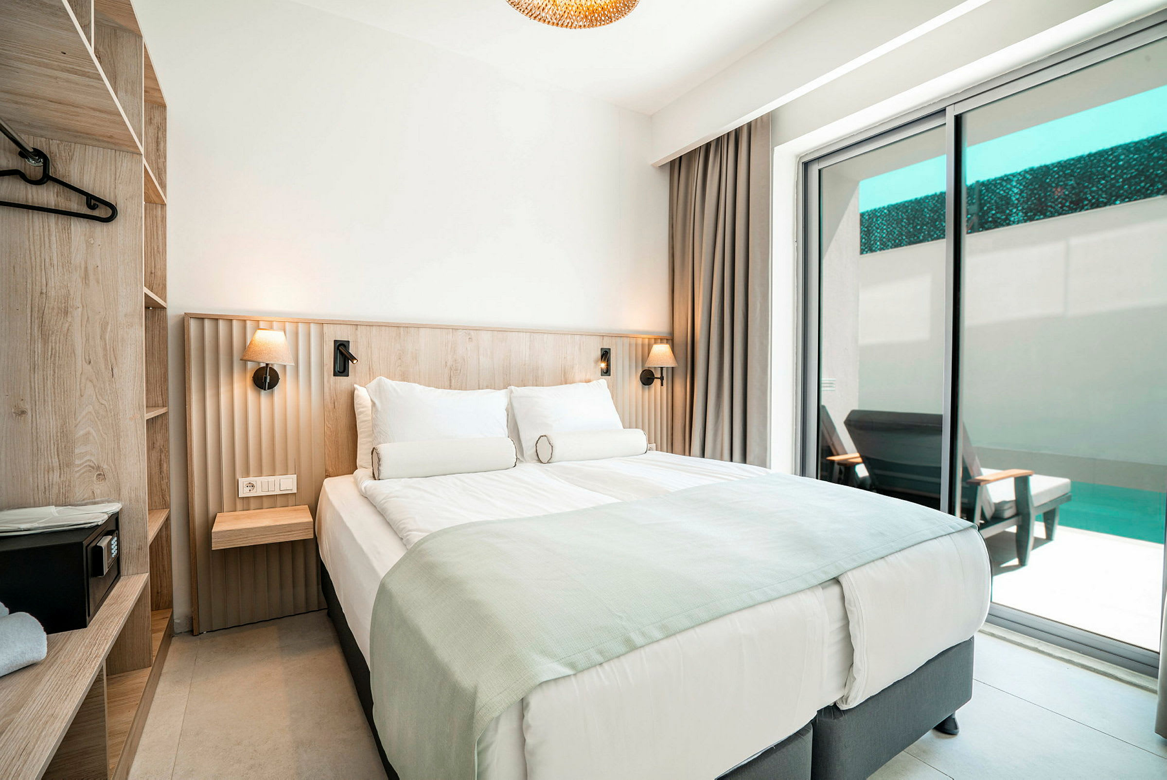 Et hotelværelse med en dobbeltseng, skuffer og en balkon med udsigt til en pool. (AI-genereret tekst)