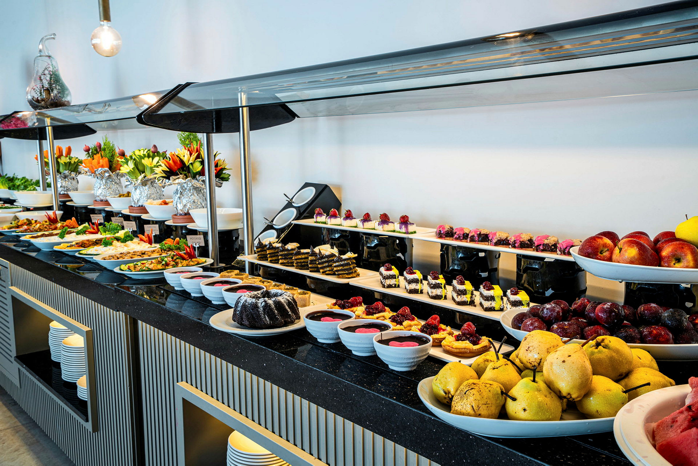 Buffetbord med et udvalg af frugt, desserter og varme retter. (AI-genereret tekst)